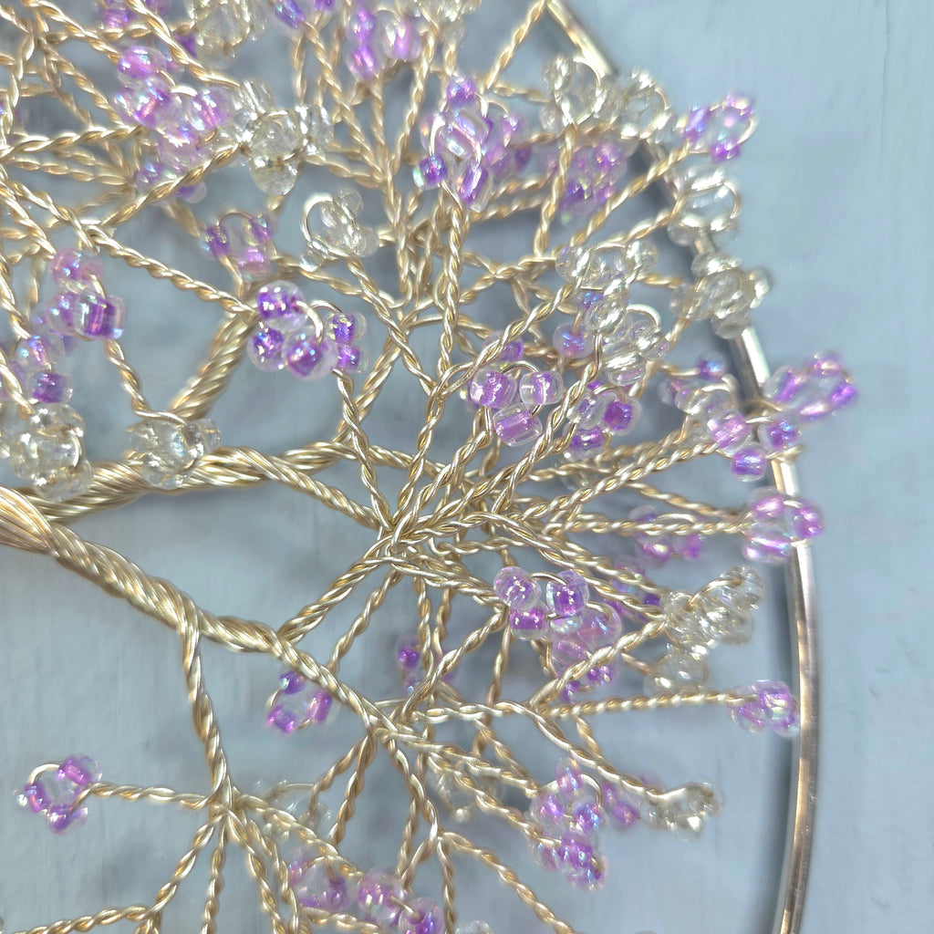 Decorative hairpin with gold wire and purple beads on a light blue background