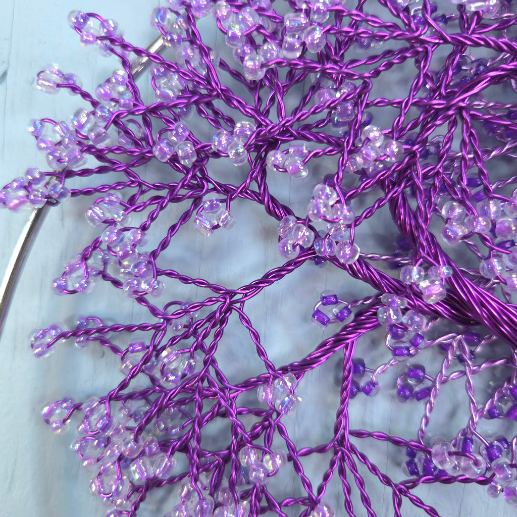 Purple decorative branch with beads on a light blue background