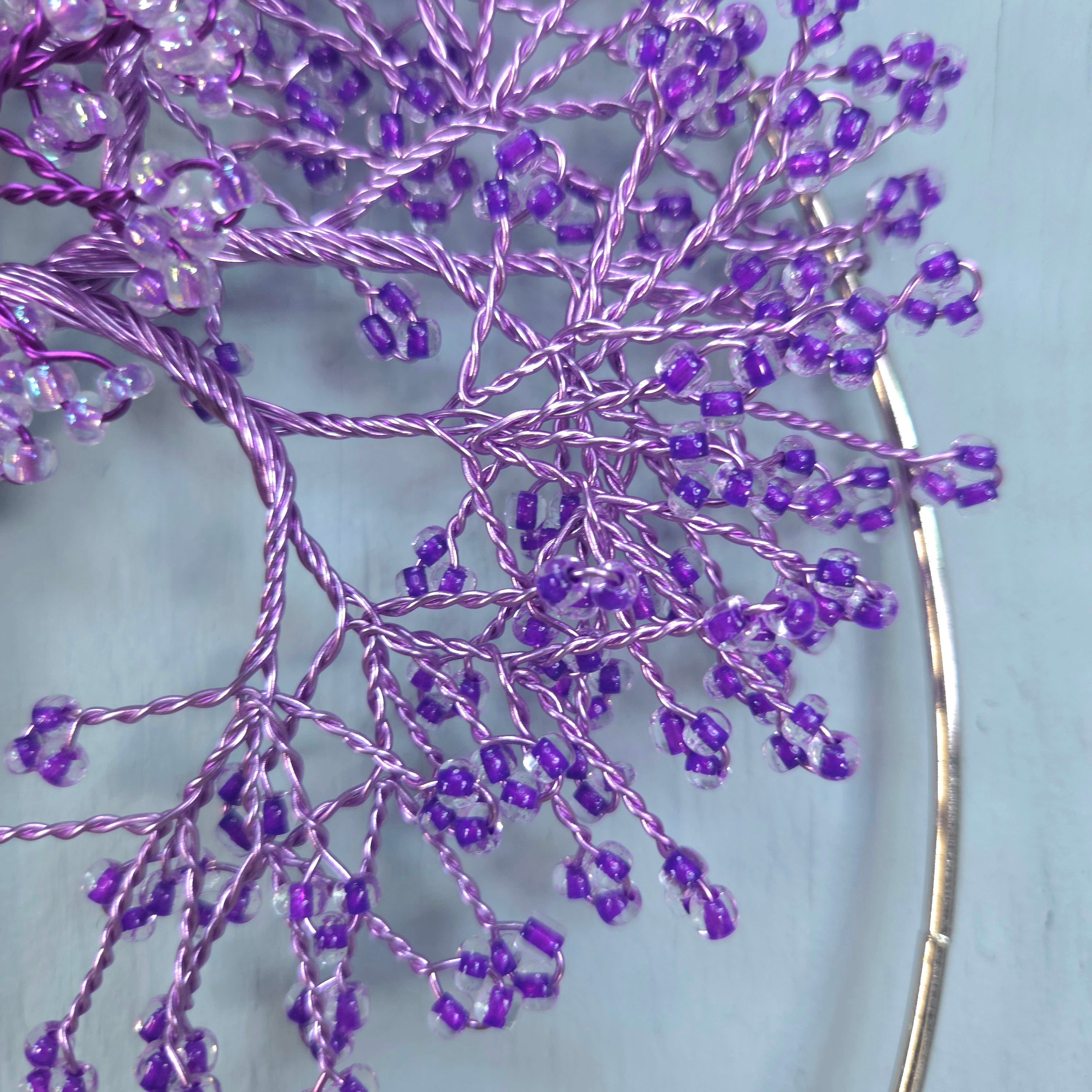 Decorative branch with purple beads on a light blue background