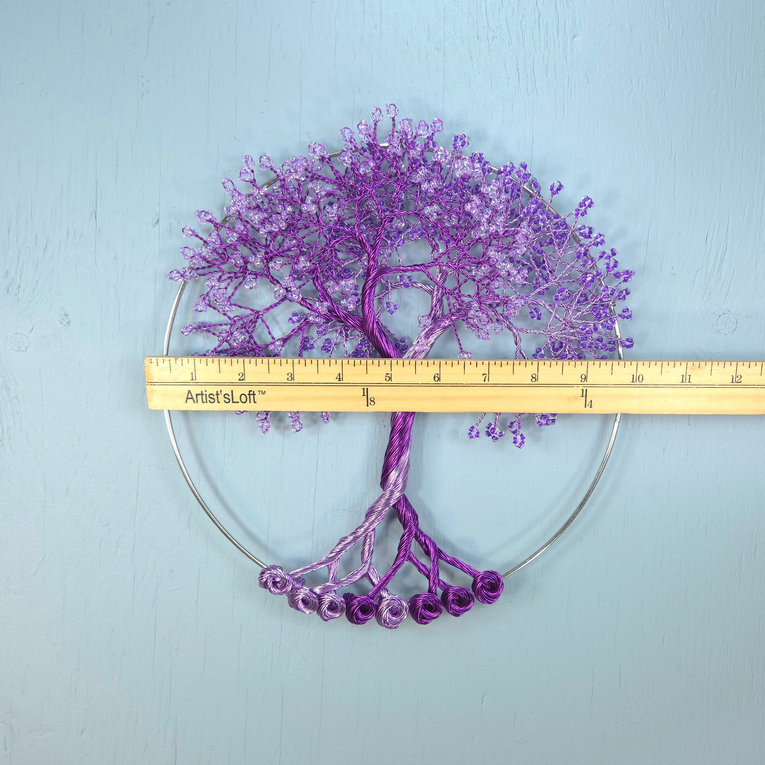 Purple decorative tree with a ruler for scale on a light blue background