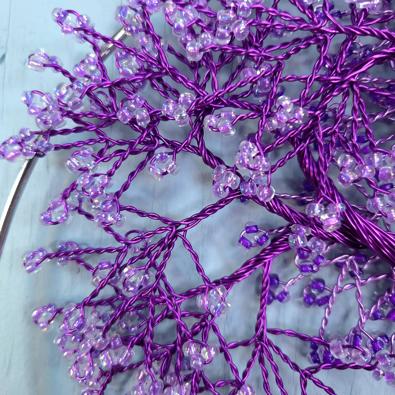 Purple decorative branch with beads on a light blue background