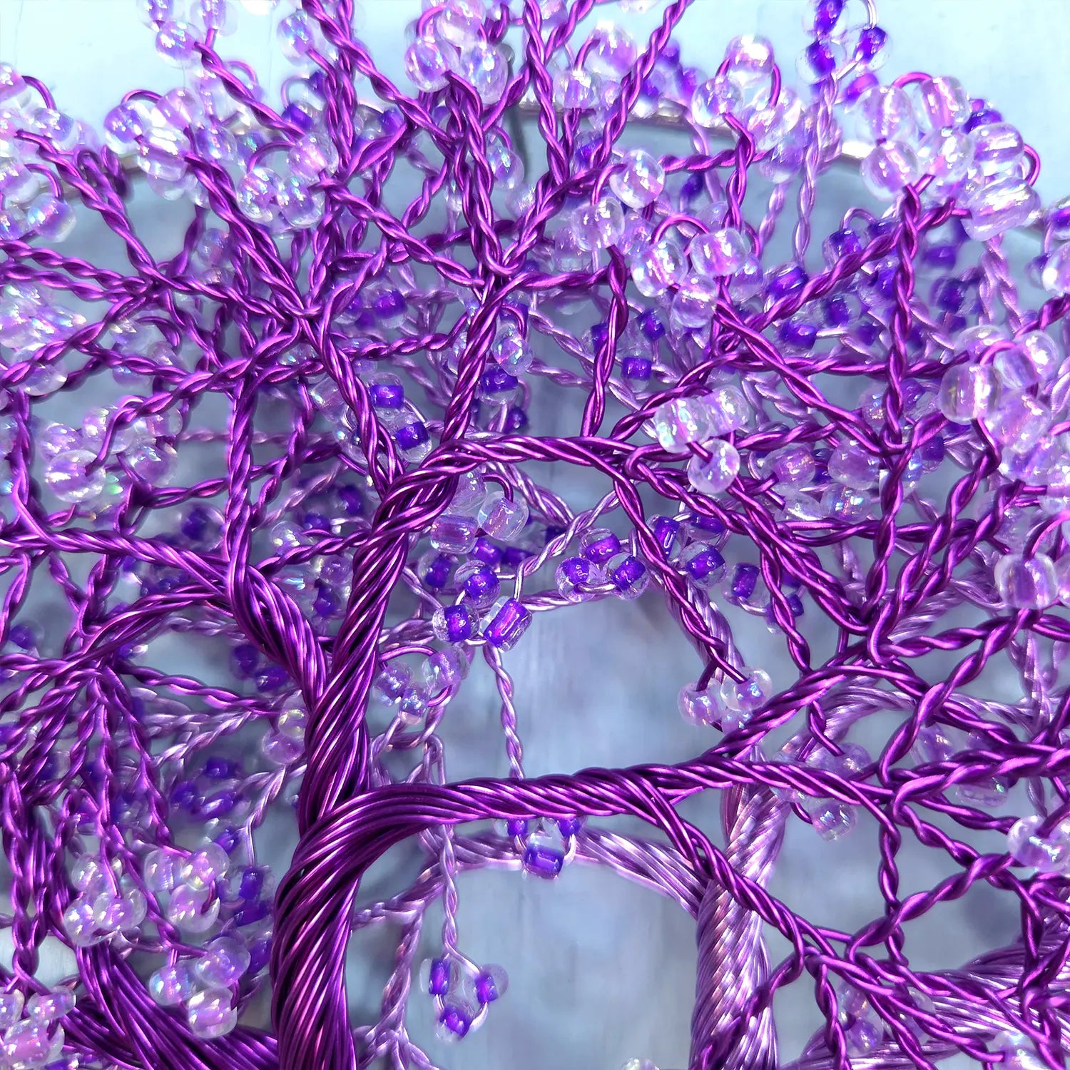 Decorative purple tree made of branches and beads against a light blue background
