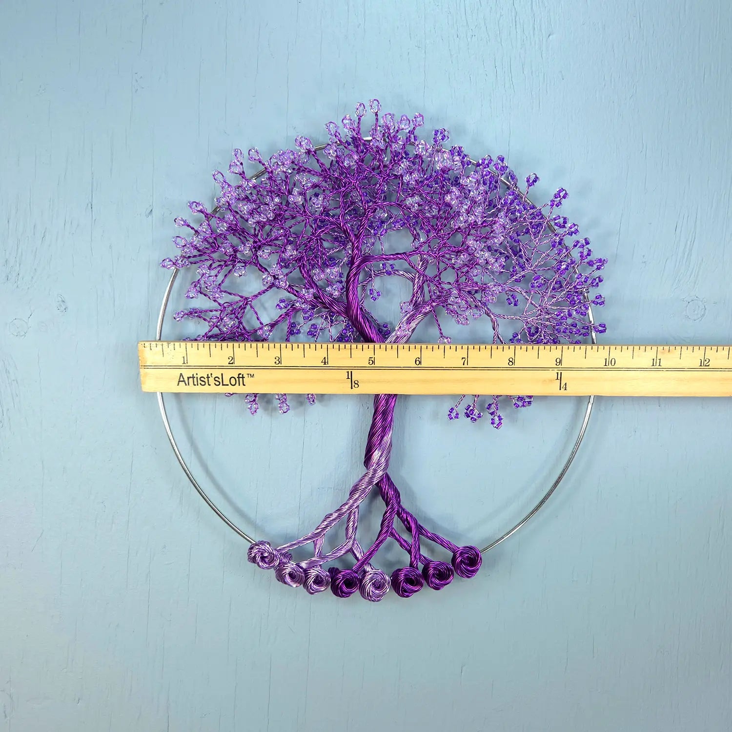 Purple decorative tree with a ruler for scale on a light blue background