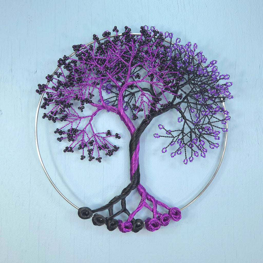 Decorative wall art of a tree with purple and black branches on a light blue background