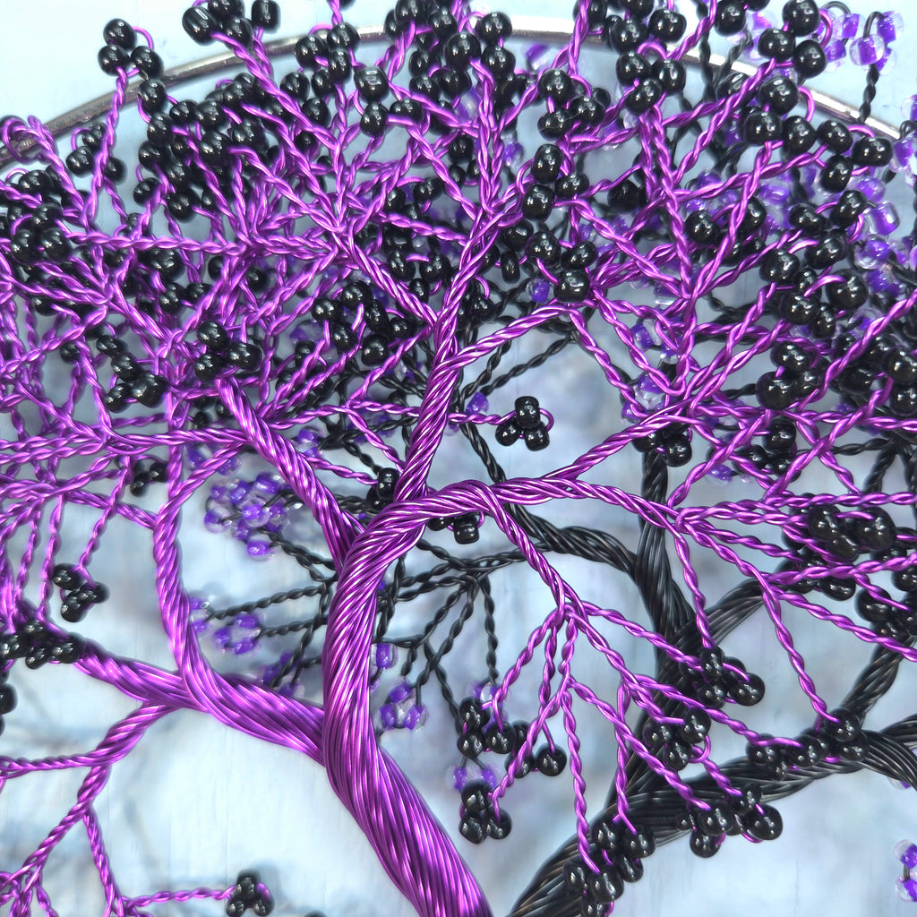 Close-up of a tree branch embroidery with purple and black thread on a white background