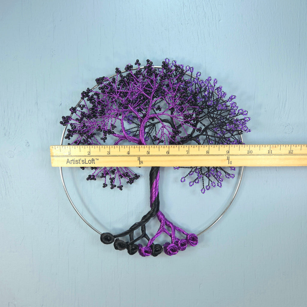 Decorative metal tree wall art with a ruler for scale on a light blue background