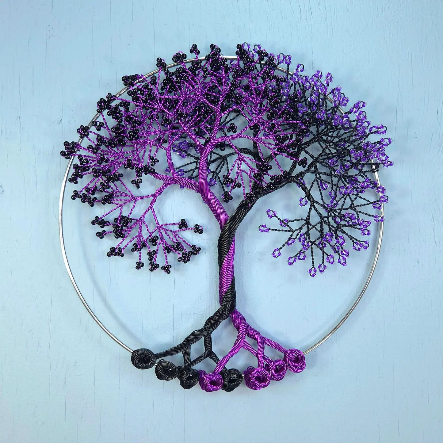 Decorative wall art of a tree with purple and black branches on a light blue background