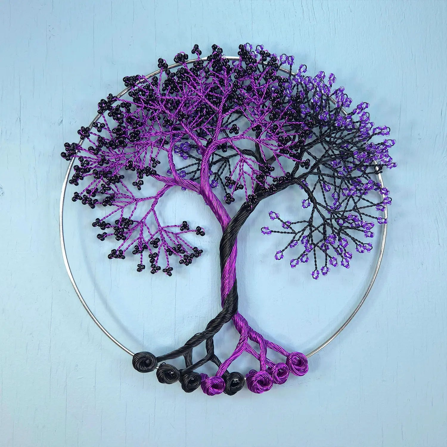 Decorative wall art of a tree with purple and black branches on a light blue background