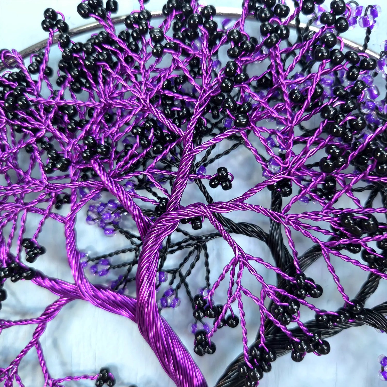 Embroidery of a tree with purple and black threads on a white background