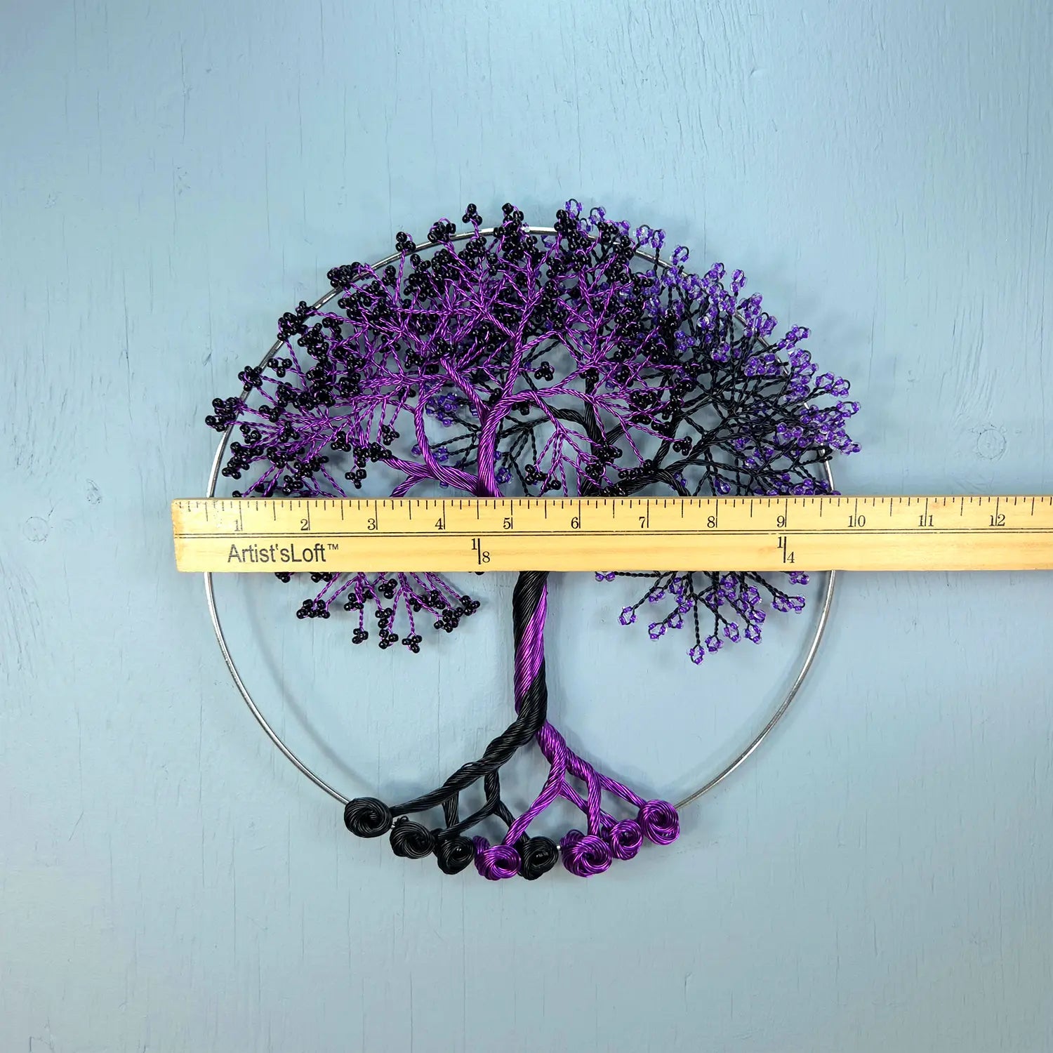 Decorative metal tree wall art with a ruler for scale on a light blue background