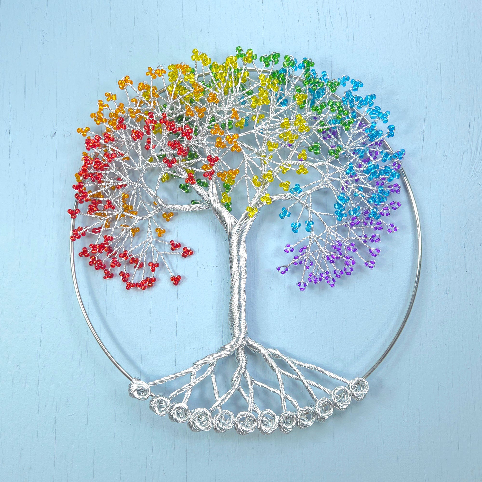 Decorative wall art of a tree with colorful beads on a light blue background