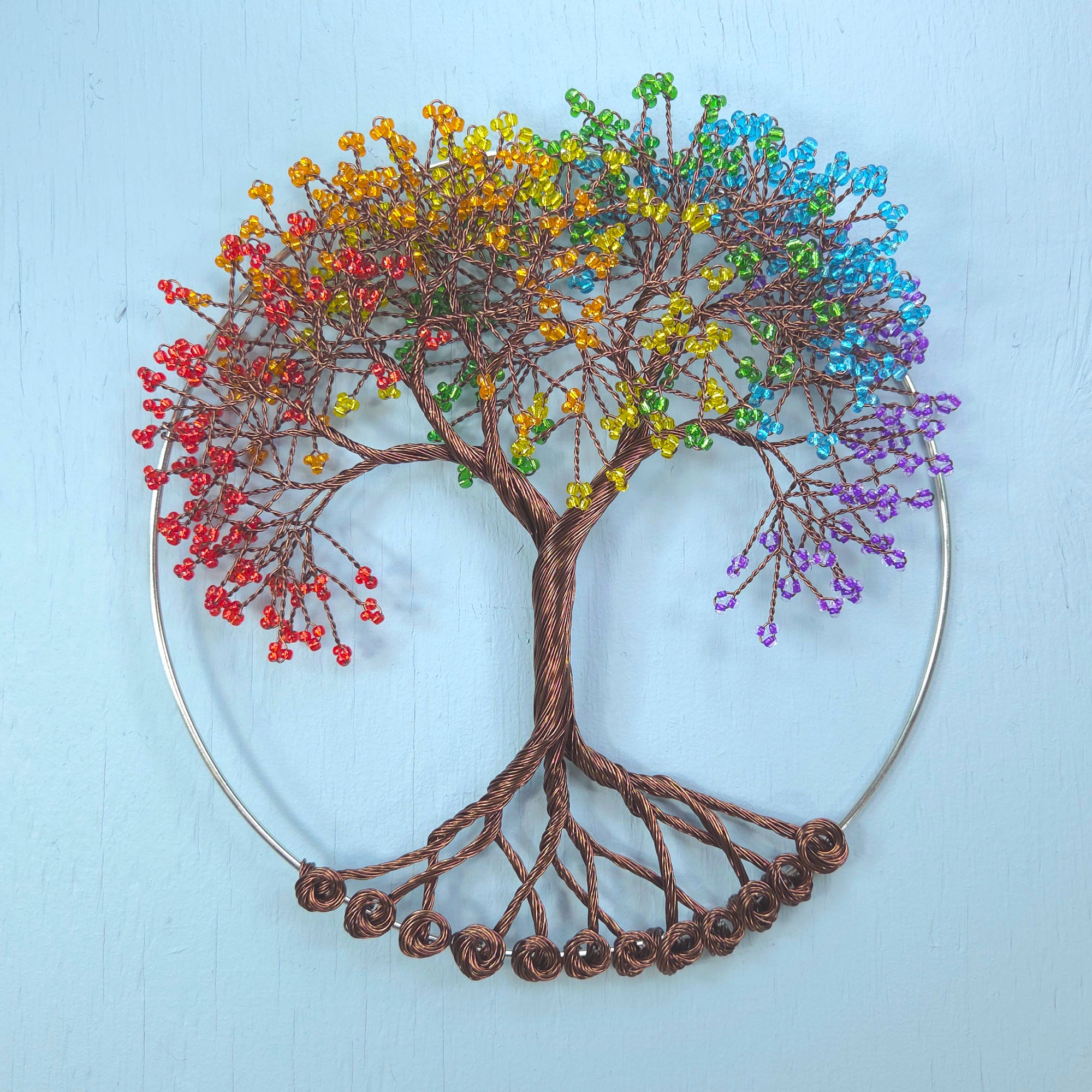 Colorful beaded tree of life against a light blue background
