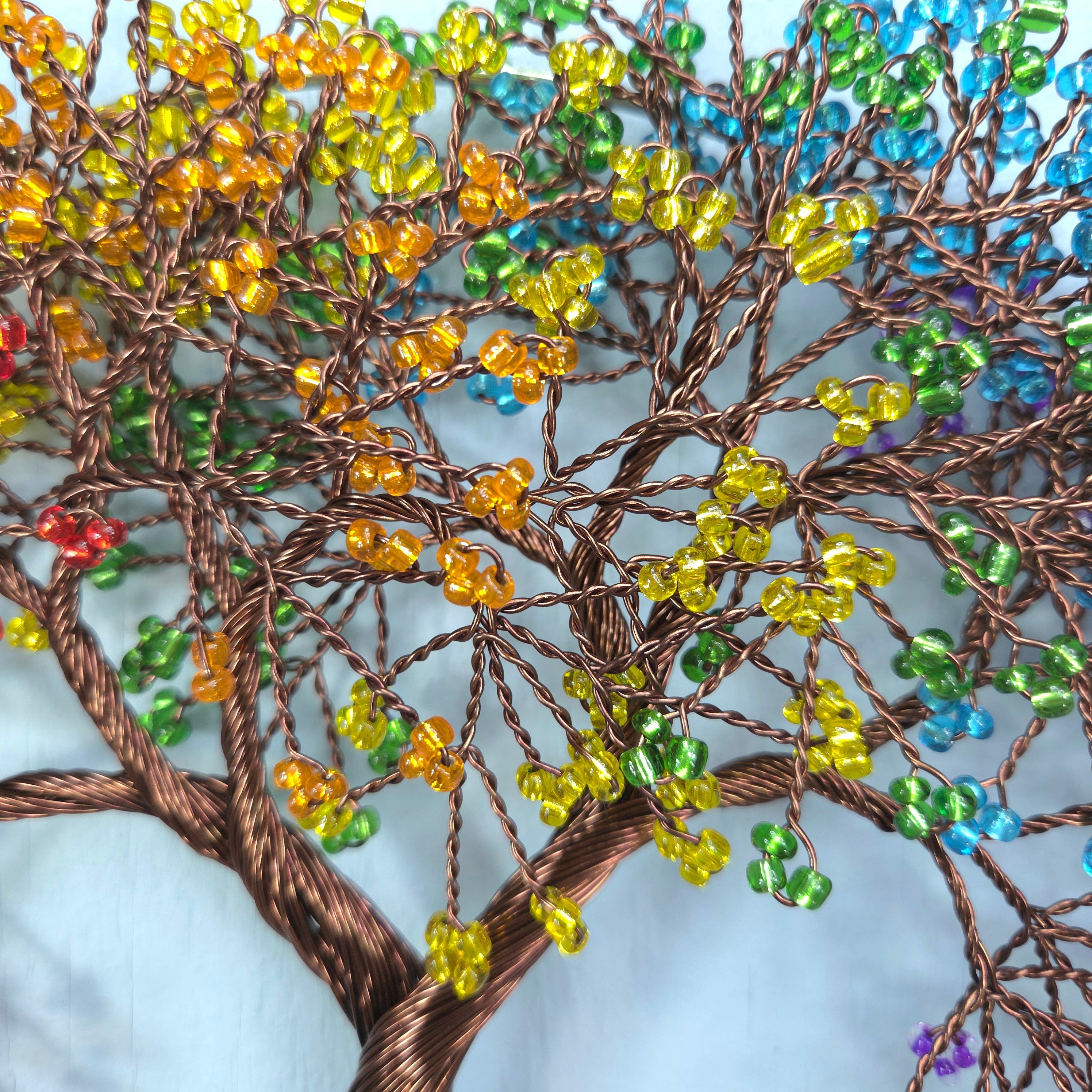 Tree sculpture with colorful beads on a textured surface