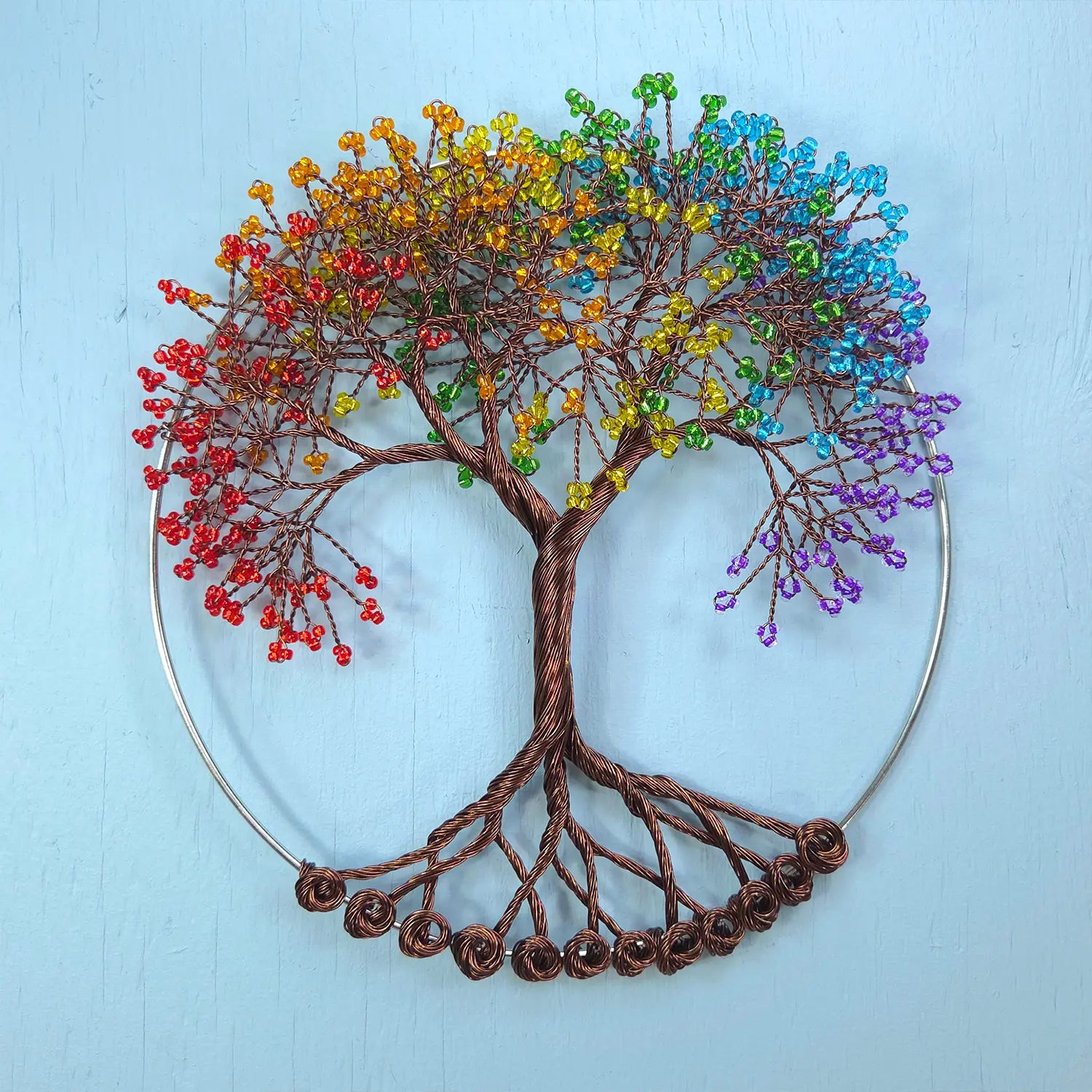 Colorful beaded tree of life against a light blue background