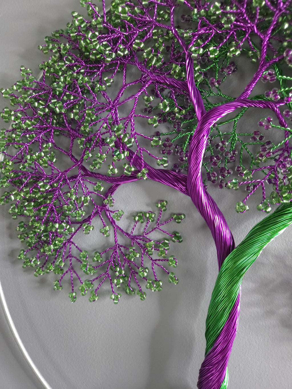 Embroidered tree design with purple and green threads on a white background