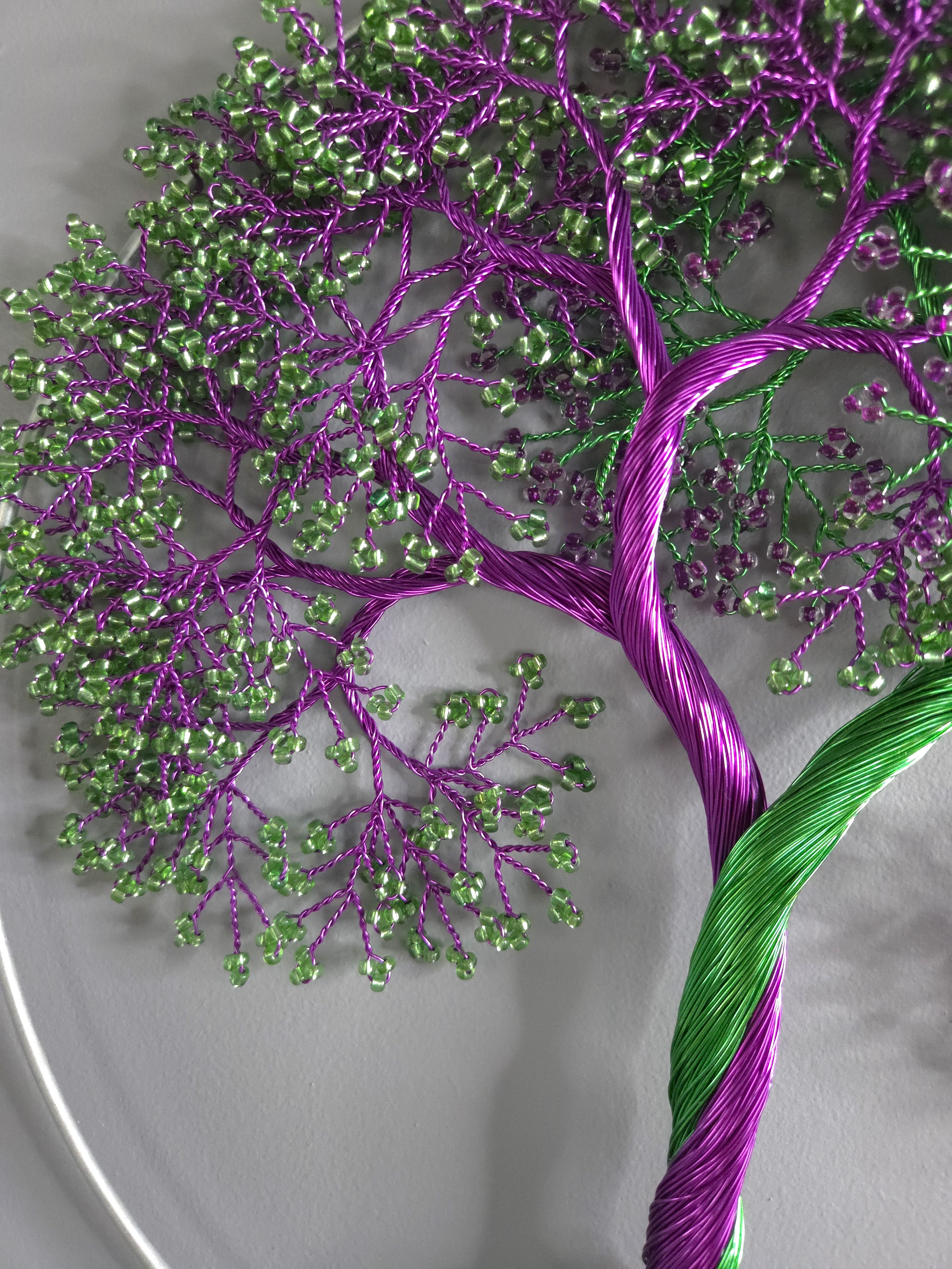 Embroidered tree design with purple and green threads on a white background