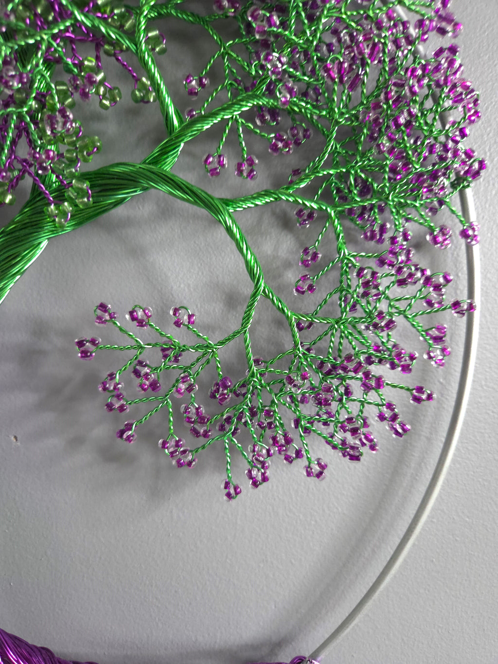 Embroidery hoop with green and purple floral pattern on a white background