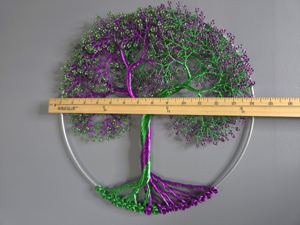 Decorative metal tree wall art with a ruler for scale on a gray background