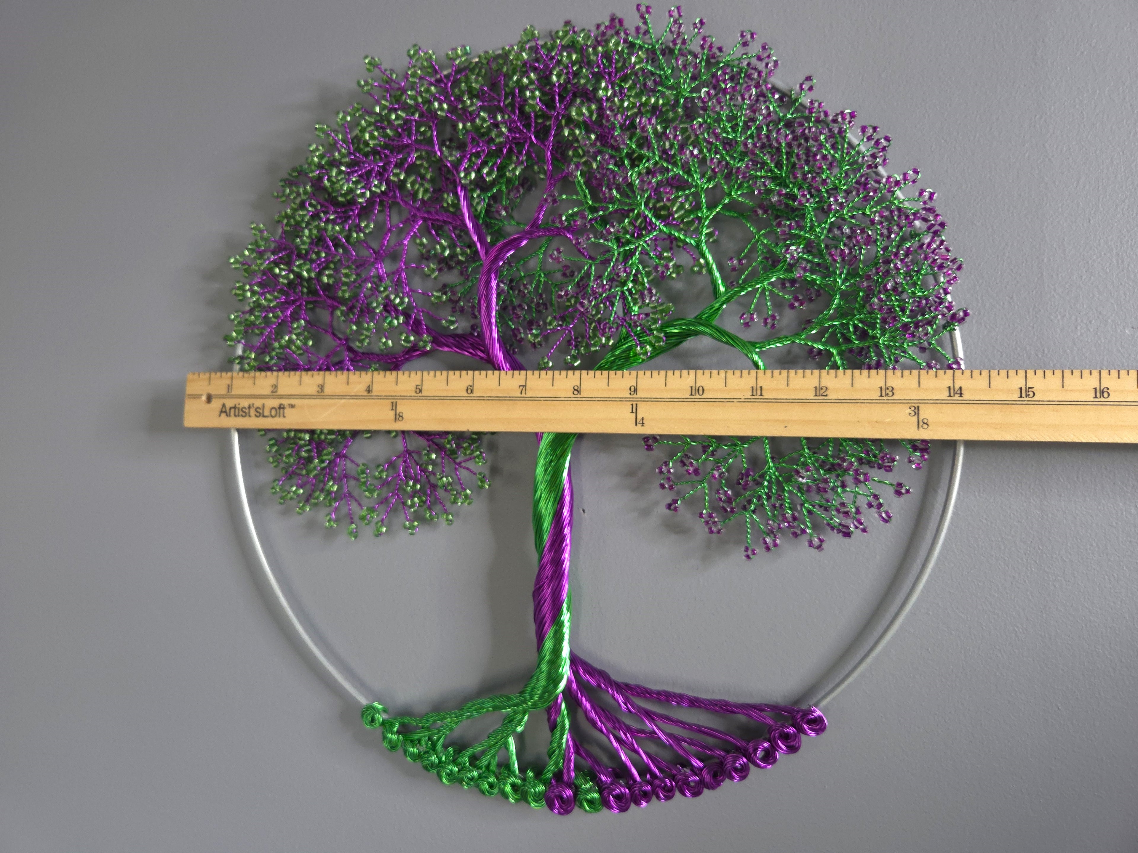 Decorative metal tree wall art with a ruler for scale on a gray background