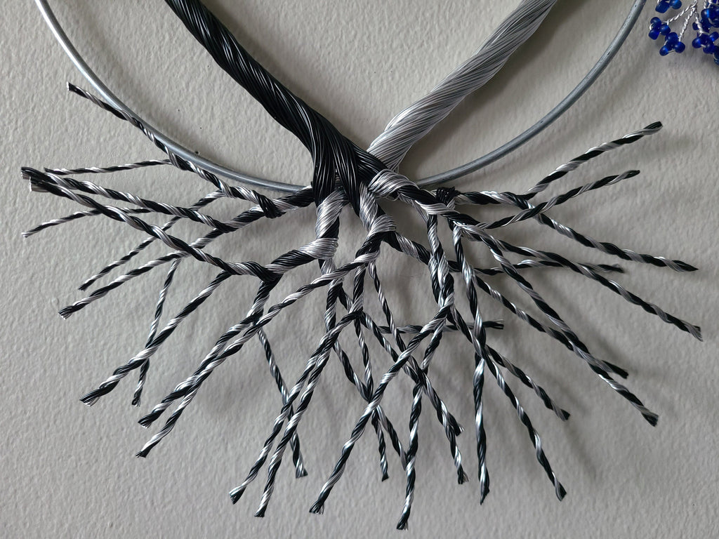 Decorative wreath with black and silver branches on a plain background
