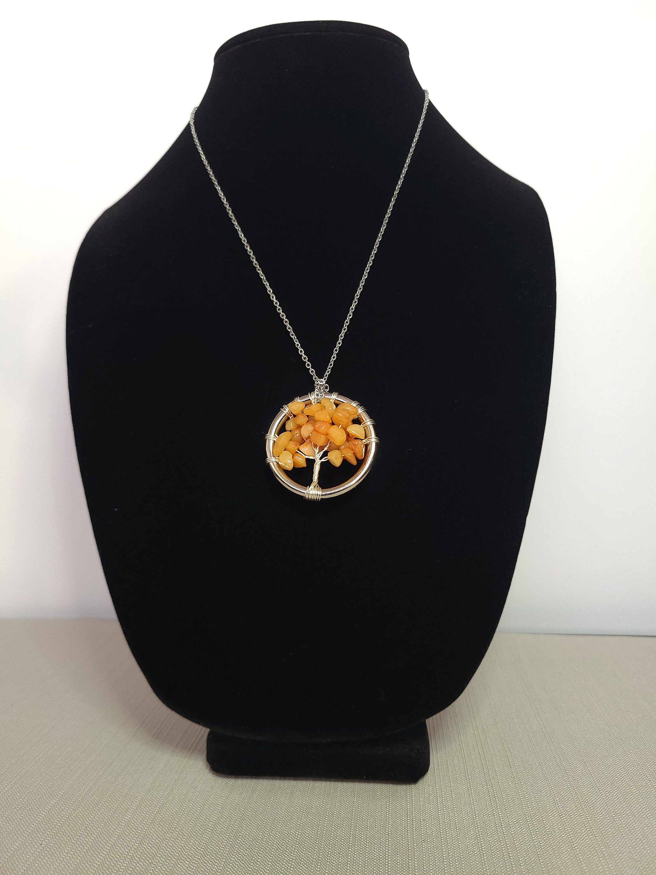 Necklace with a tree-shaped pendant on a black bust against a white background