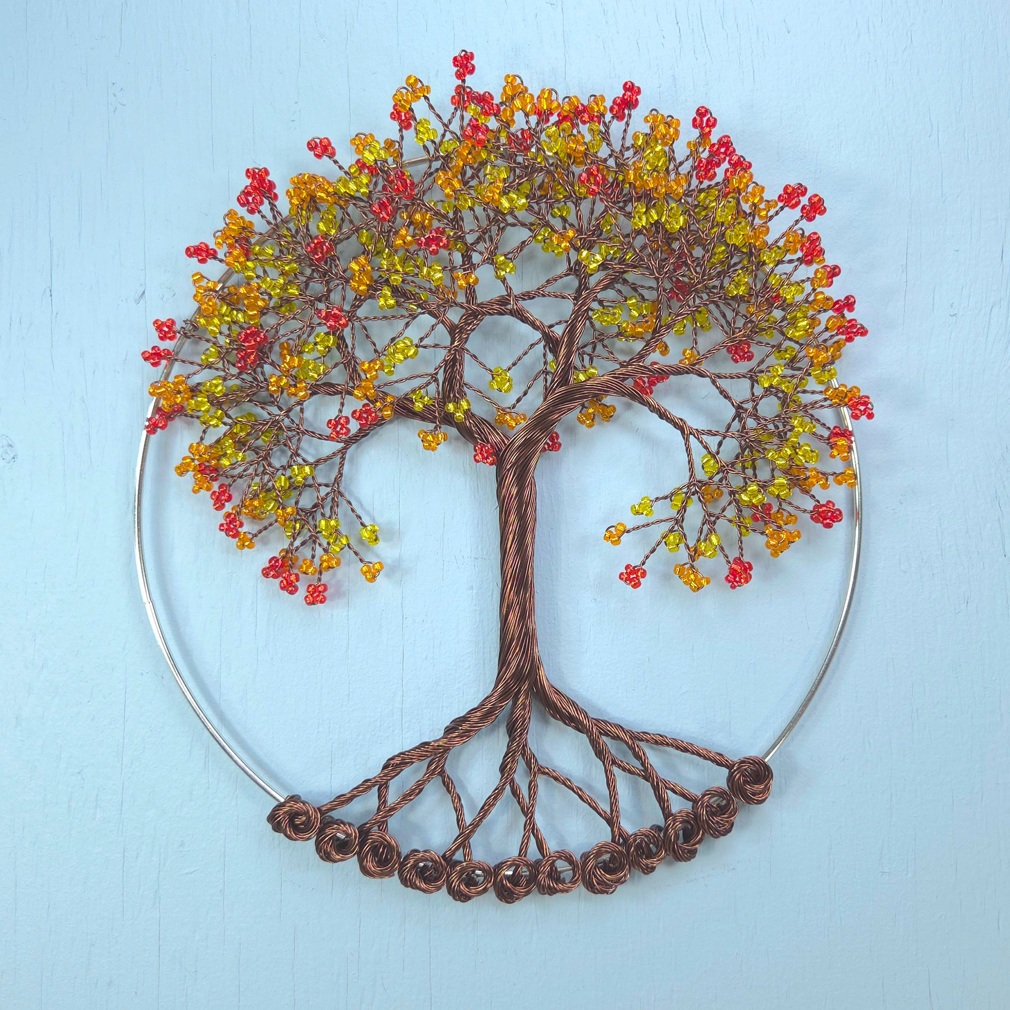 Decorative wall art of a tree with colorful berries on a light blue background