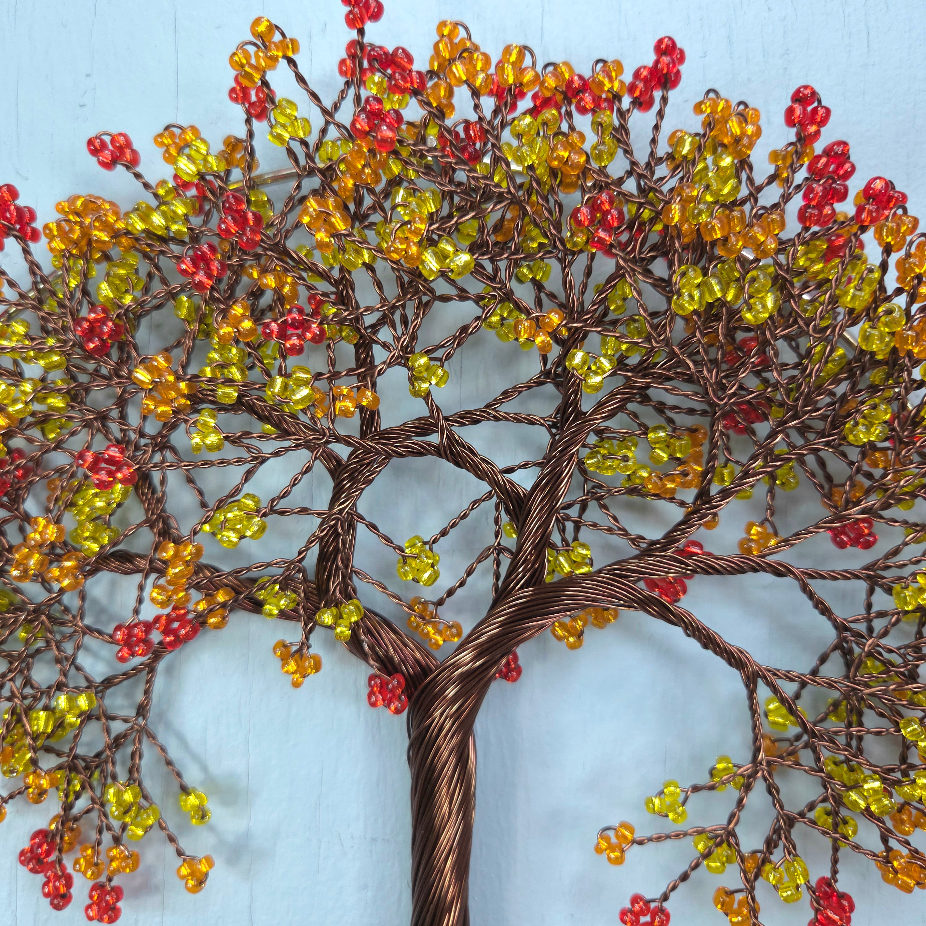 Decorative wall art of a tree with colorful beads on a light blue background