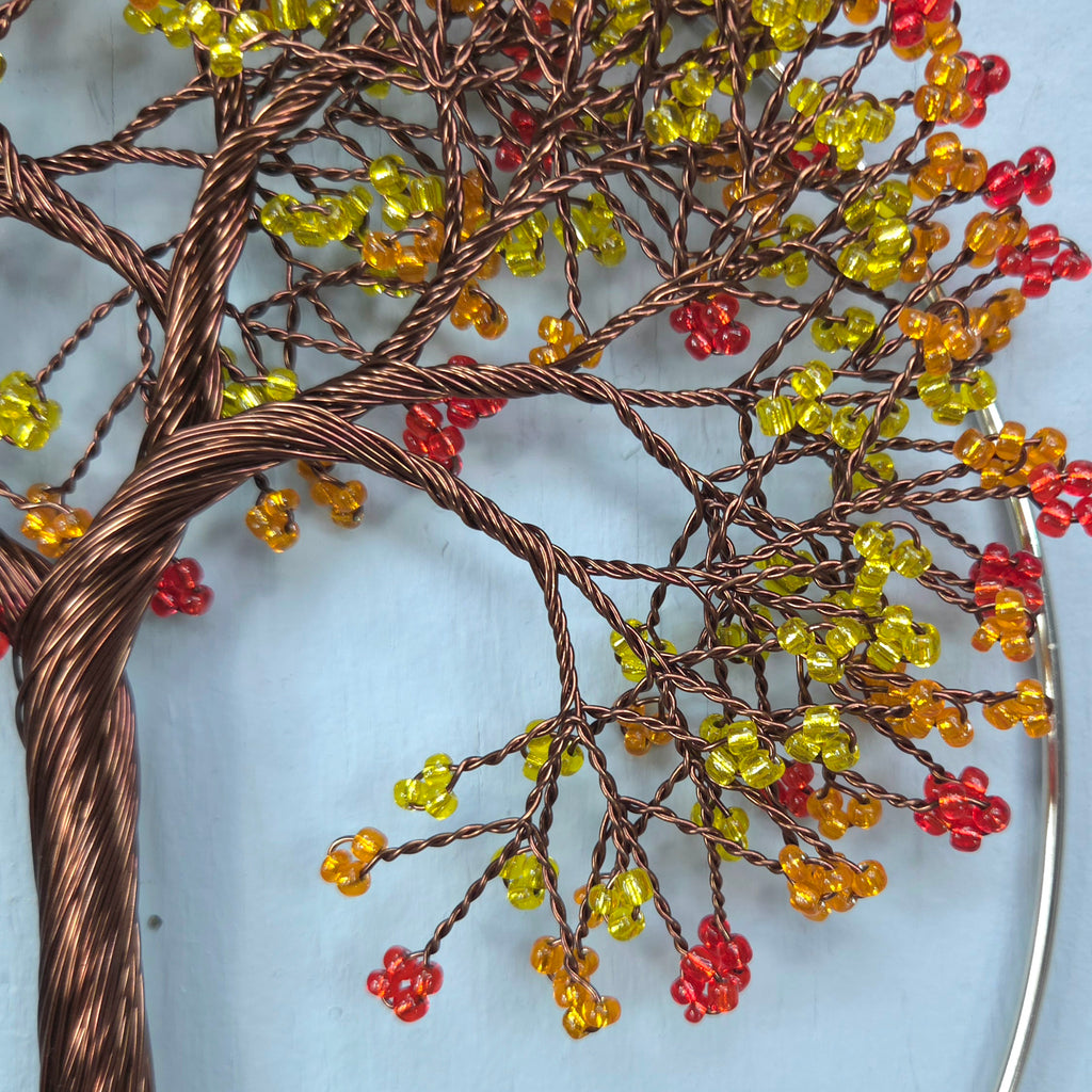 Decorative wall art of a tree with colorful beads on a light blue background