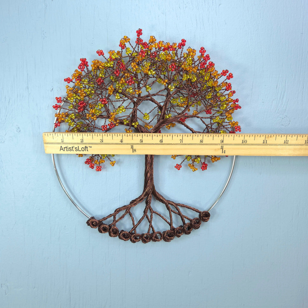 Decorative wall art of a tree with autumn leaves and berries, measured against a ruler on a light blue background.