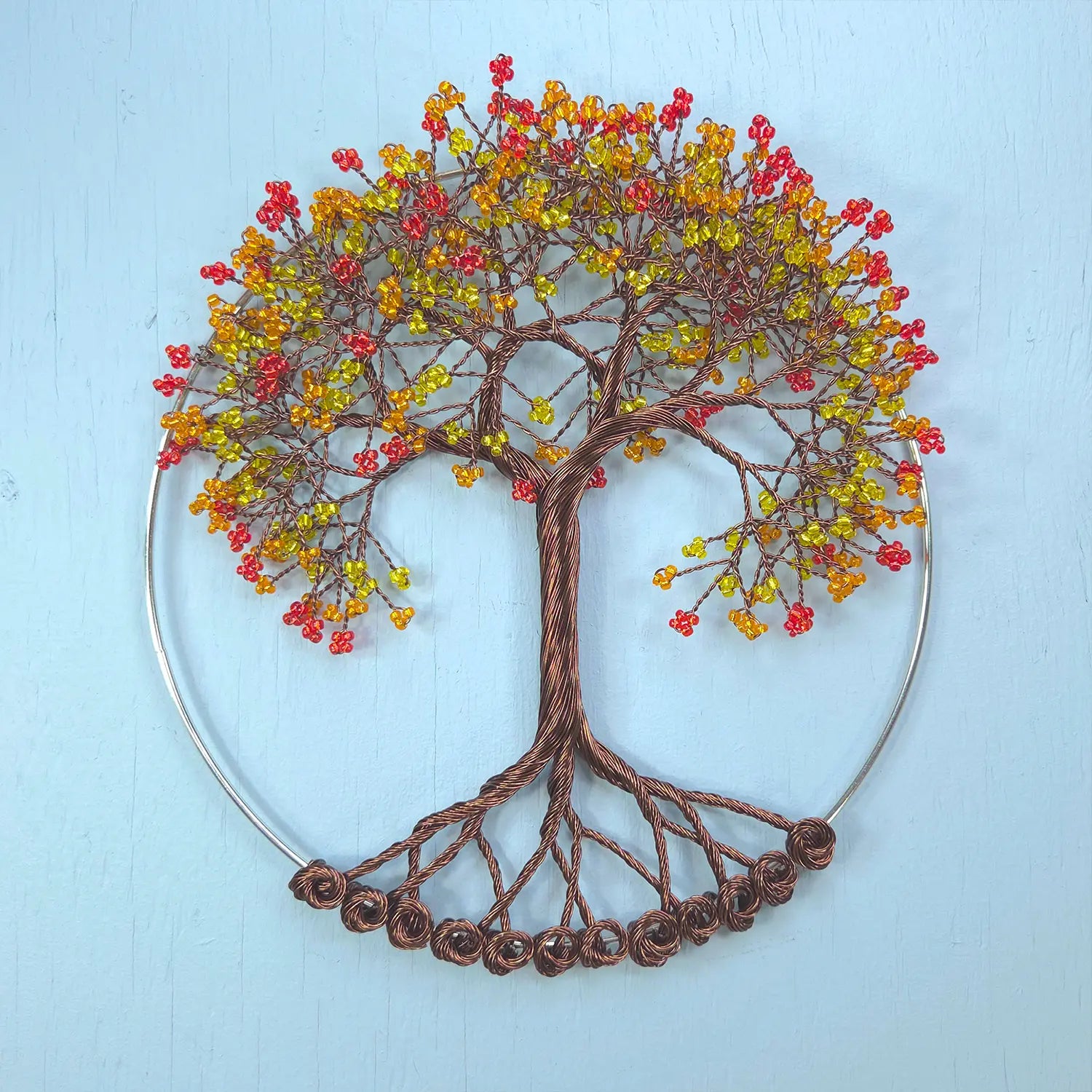 Decorative wall art of a tree with colorful berries on a light blue background