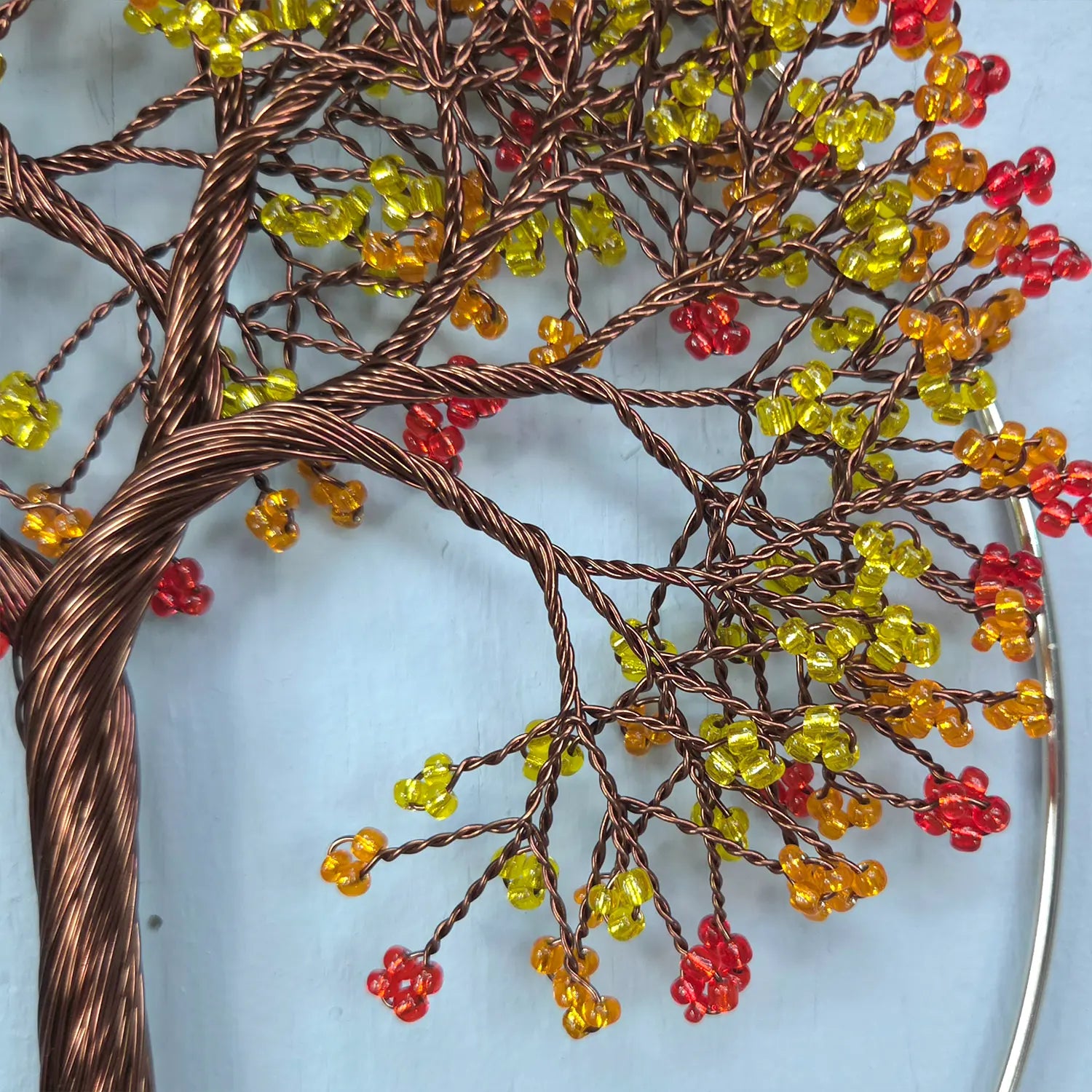 Decorative wall art of a tree with colorful beads on a light blue background