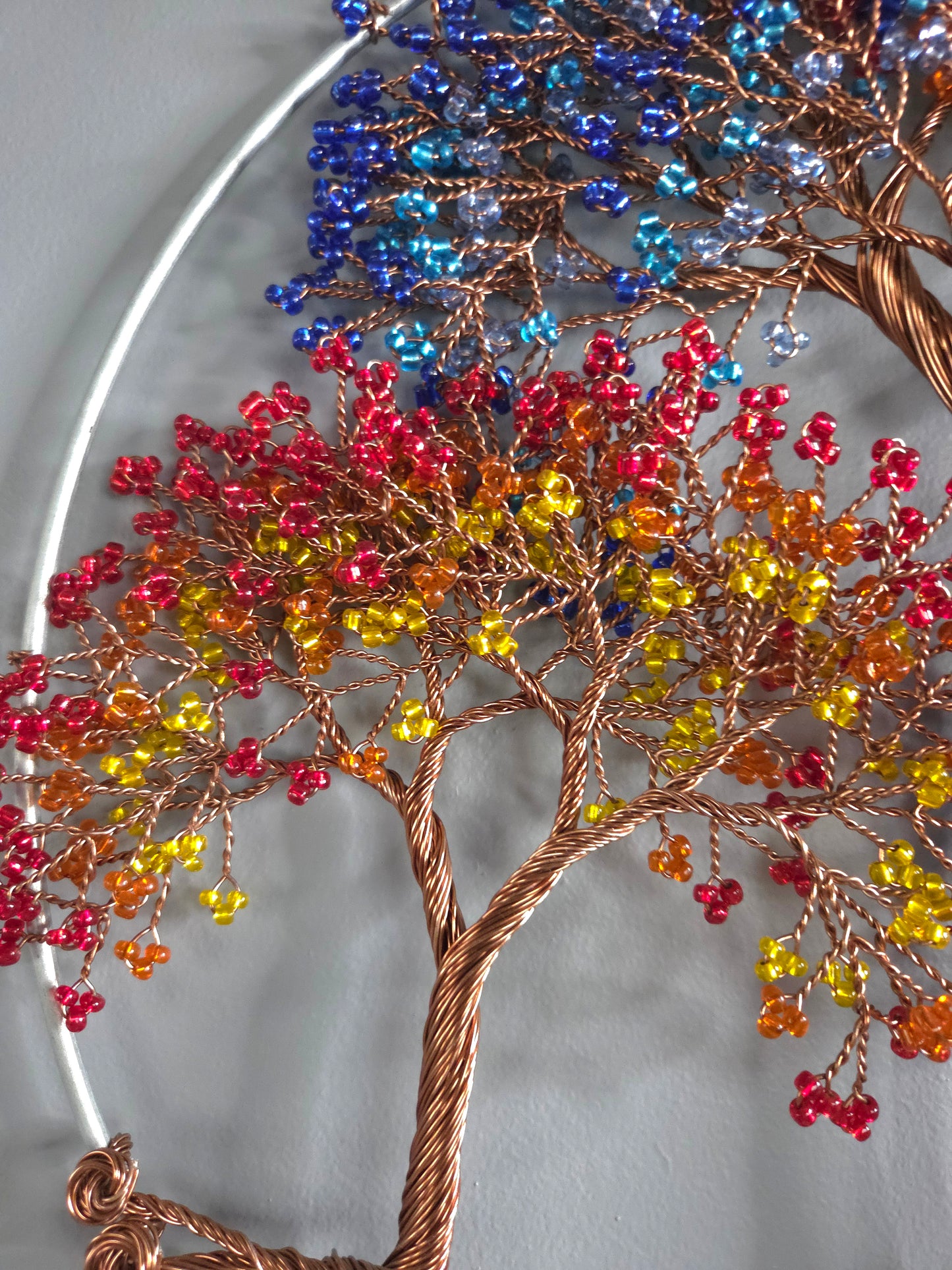 Decorative tree sculpture with colorful beads on a plain background