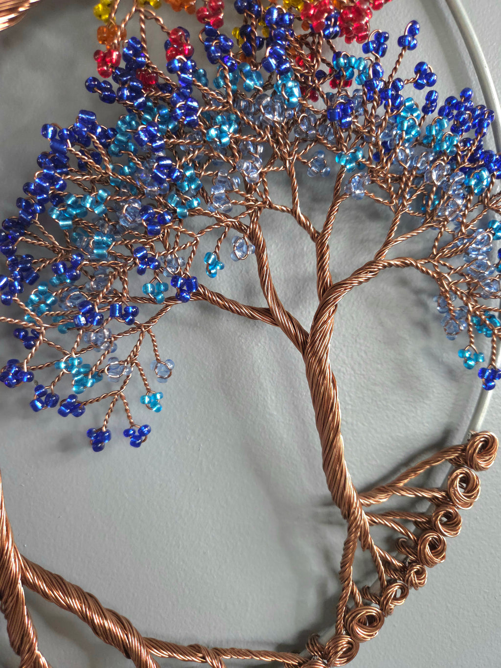 Decorative tree sculpture with colorful beads on a plain background