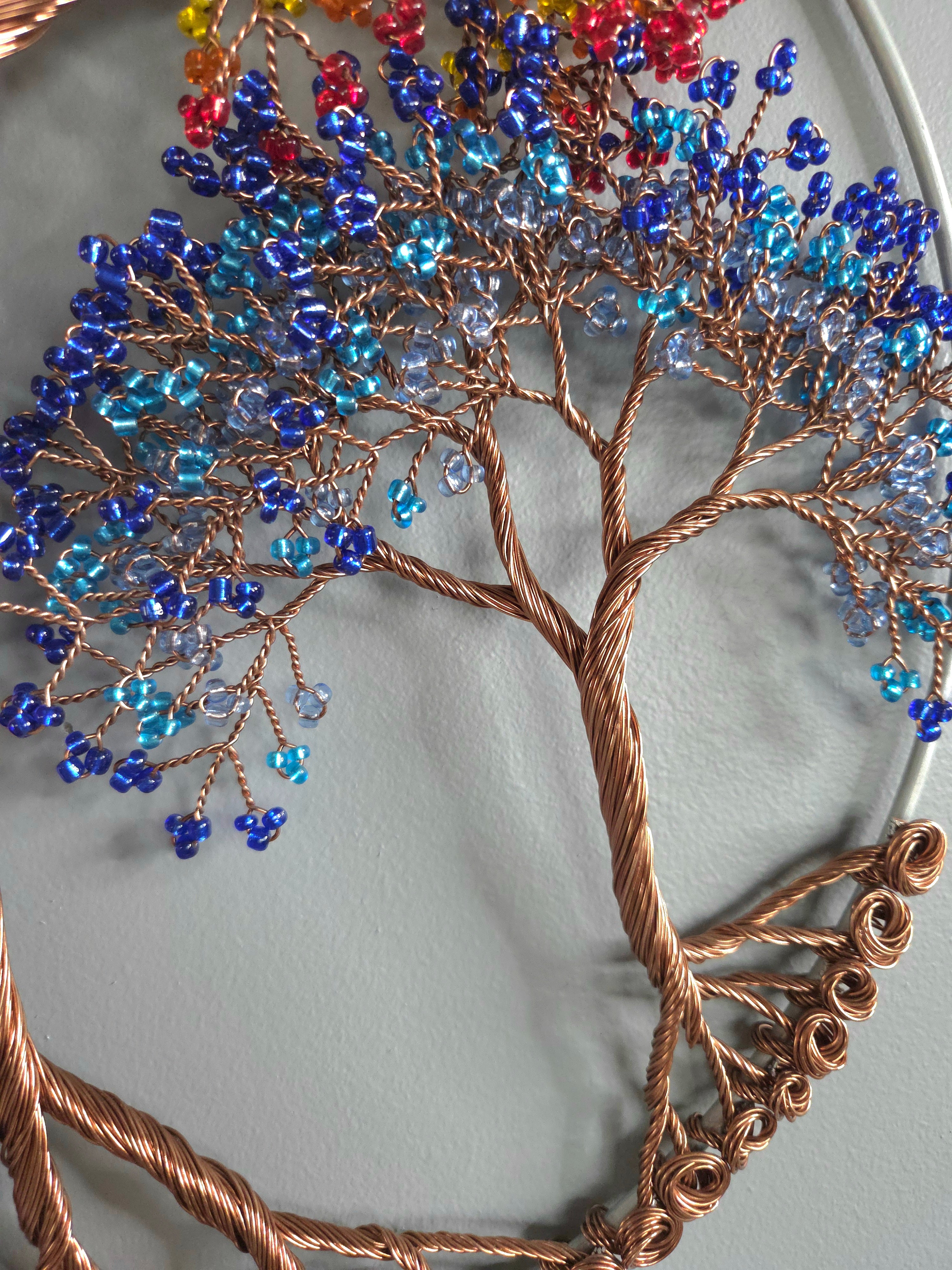 Decorative tree sculpture with colorful beads on a plain background
