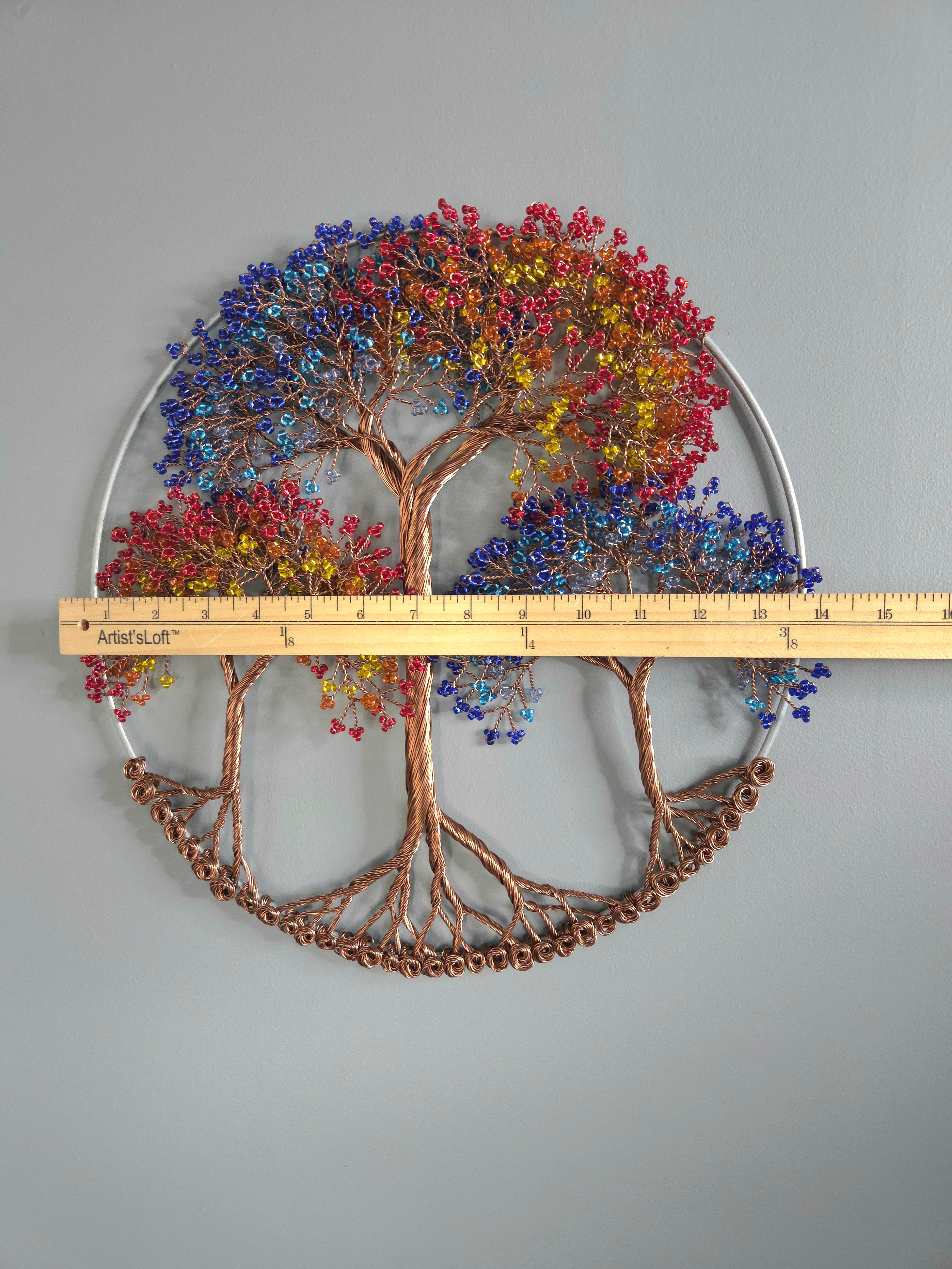 Decorative wall art of a tree with colorful leaves and a ruler for scale on a gray background