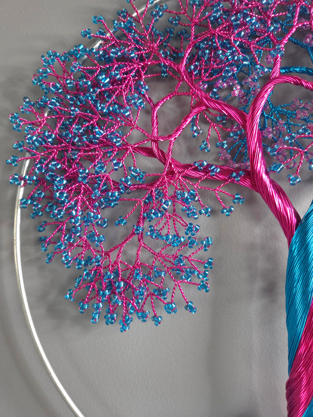 Close-up of a beaded pink and blue tree branch on a gray background