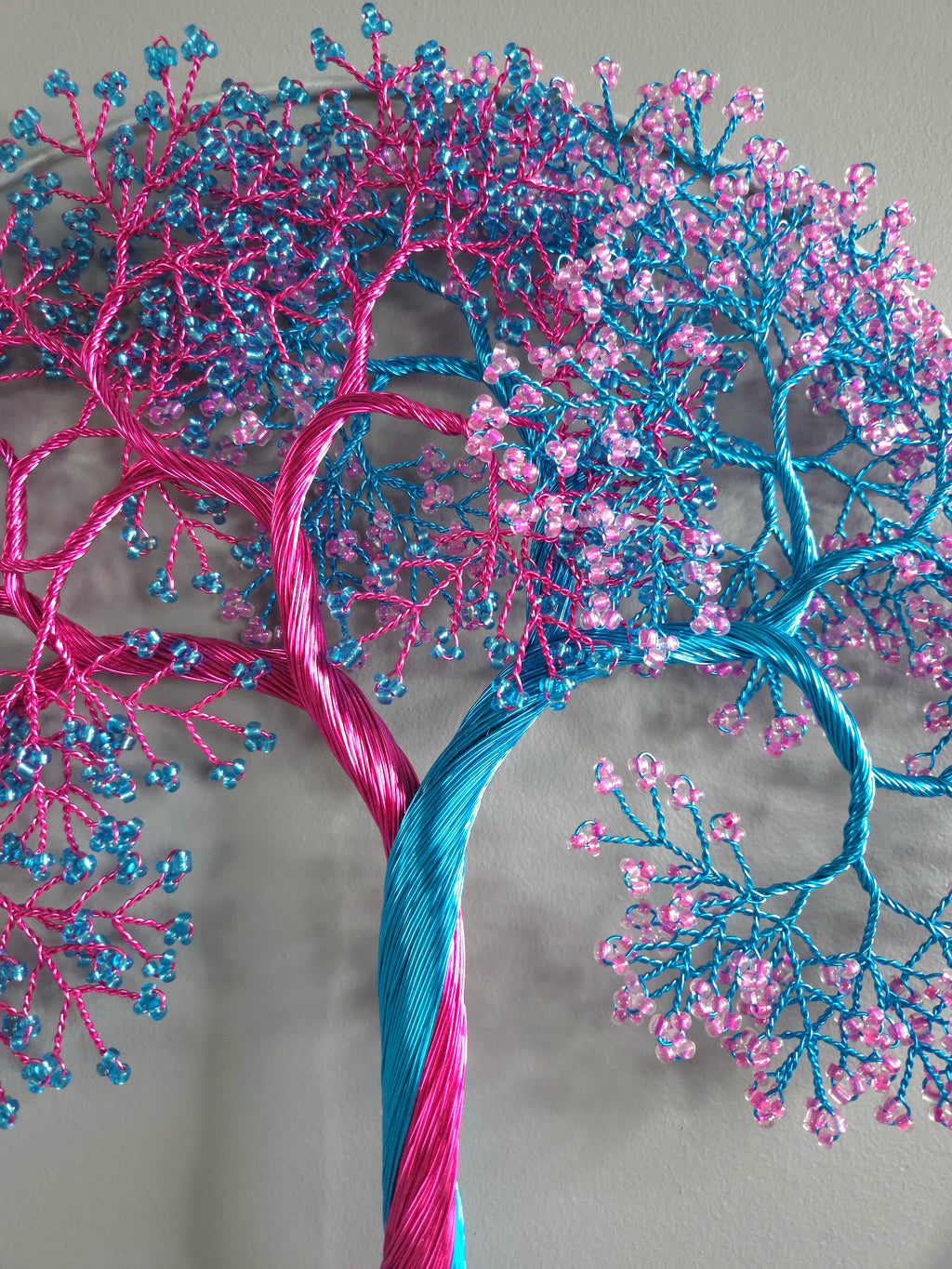 Decorative tree made of pink and blue threads on a gray background