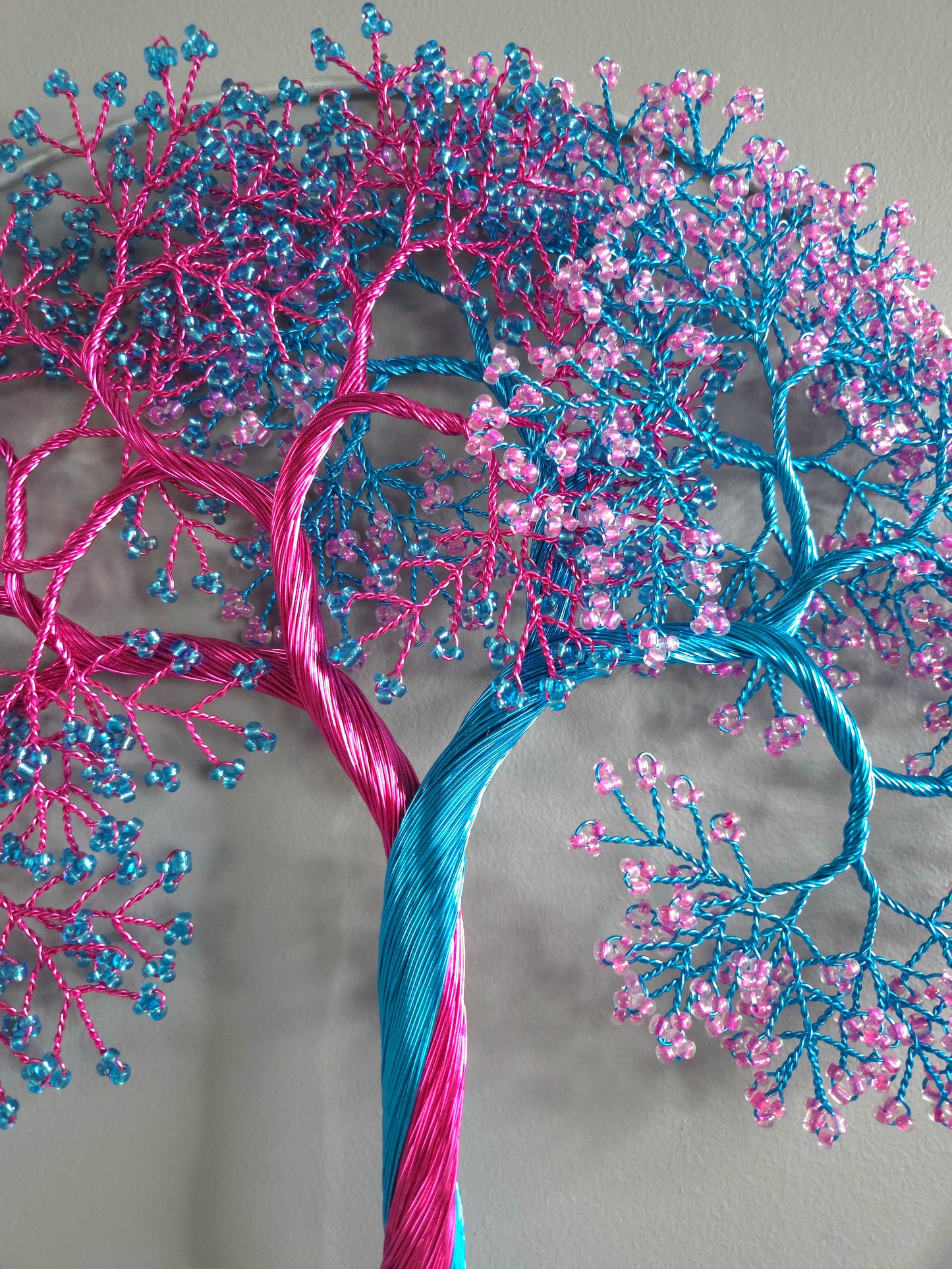 Decorative tree made of pink and blue threads on a gray background
