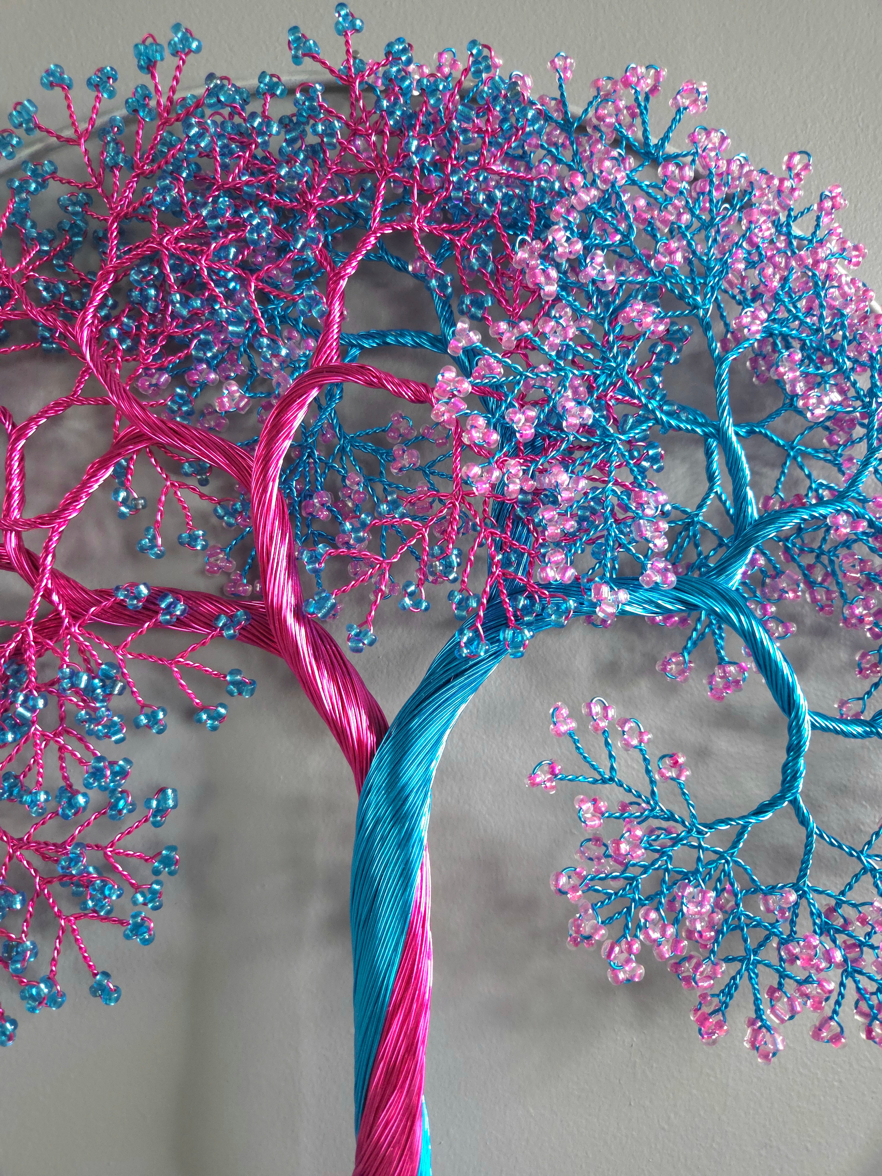 Decorative tree made of pink and blue threads on a gray background