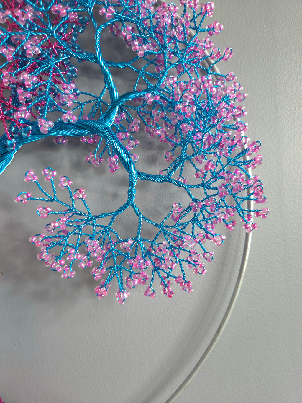 Decorative wall art with blue and pink branches on a gray background