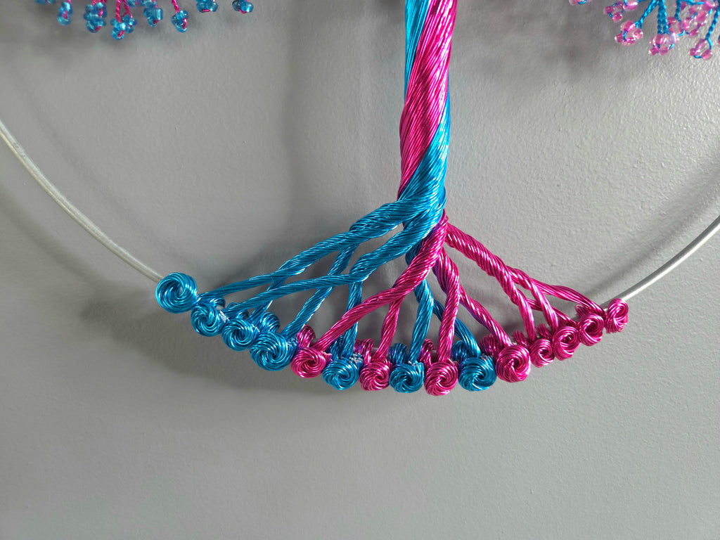 Close-up of blue and pink beaded necklace on a light gray background