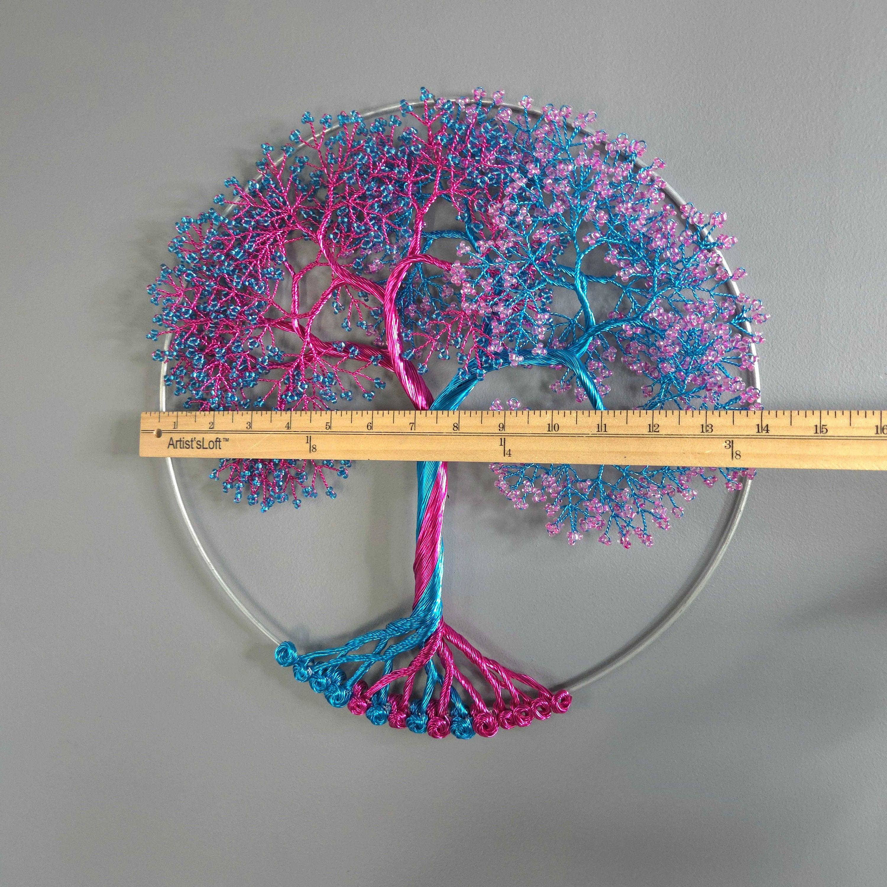 Decorative wall piece with pink and blue branches on a gray background, measured by a ruler.