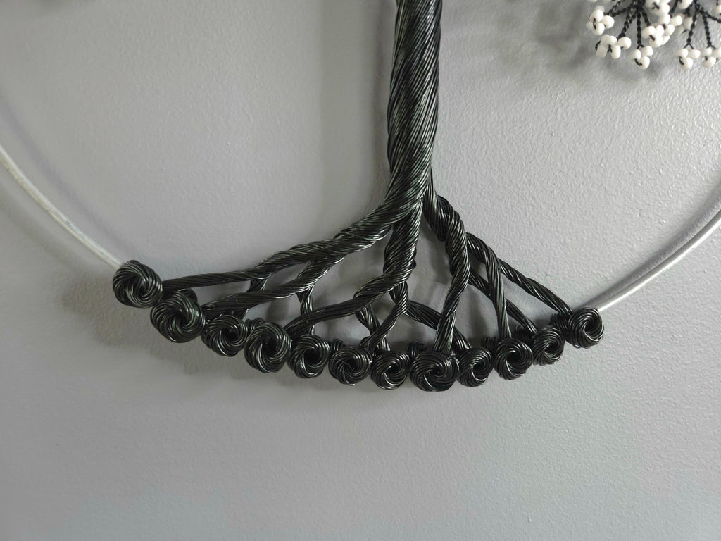 Close-up of a black wire necklace on a light gray background