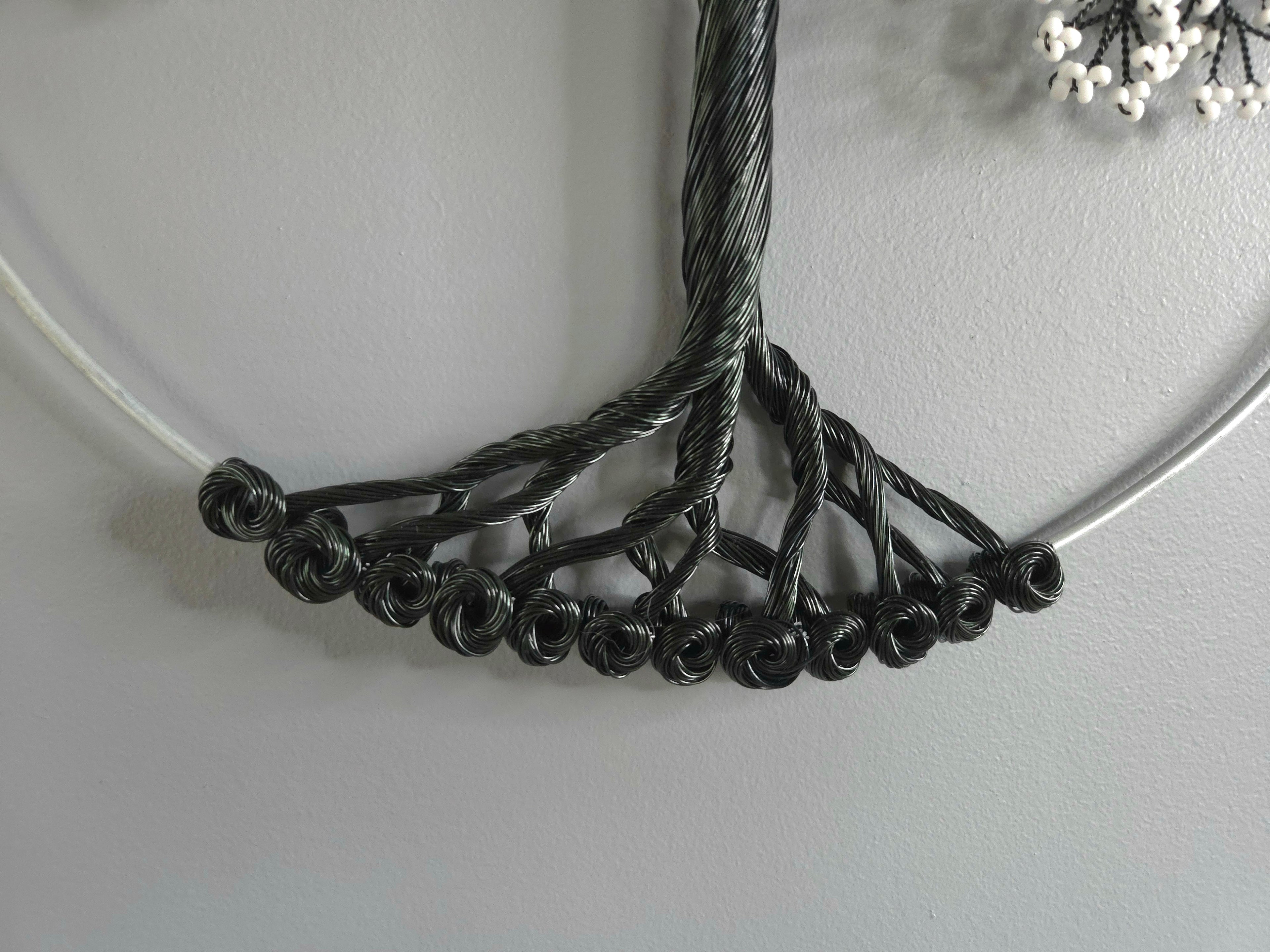 Close-up of a black wire necklace on a light gray background