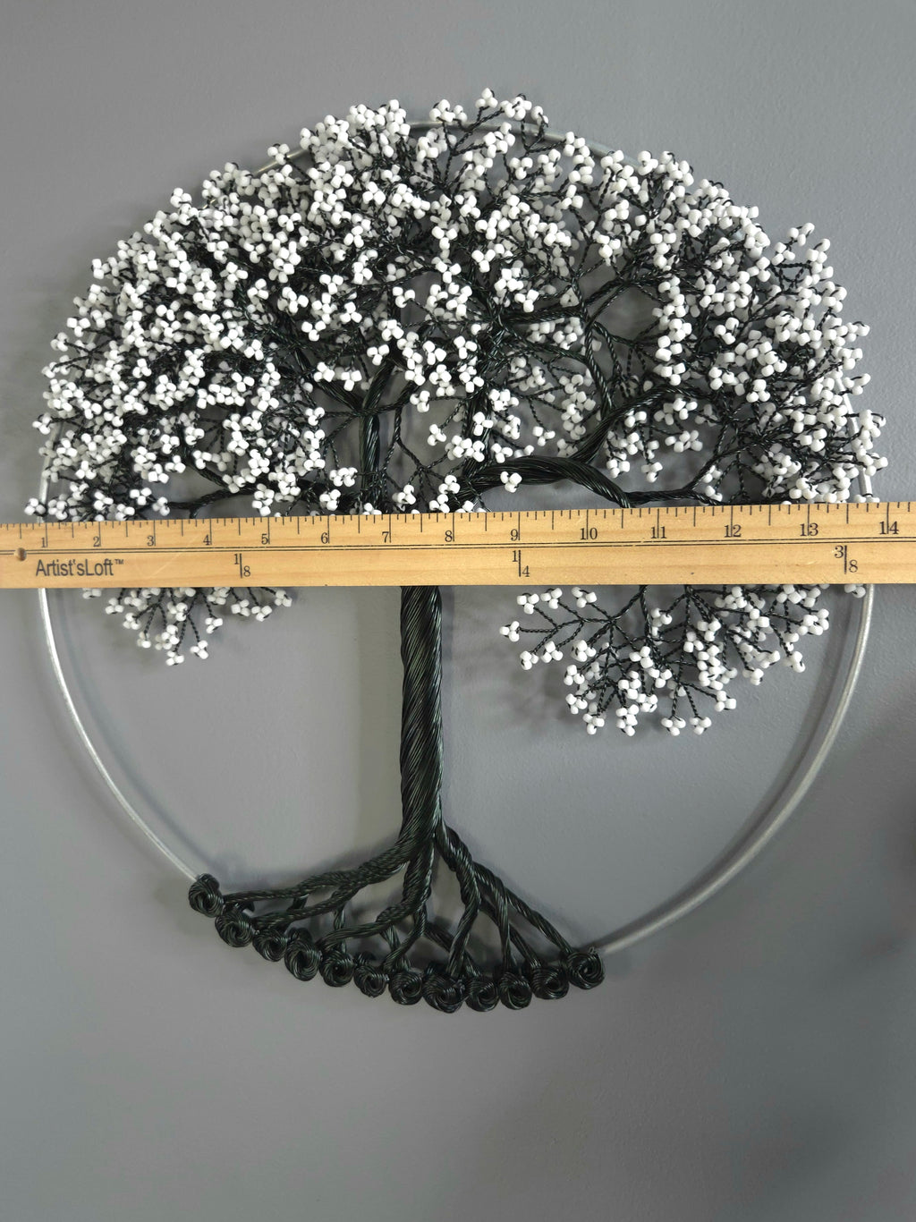 Decorative tree with white berries and a ruler for scale on a gray background