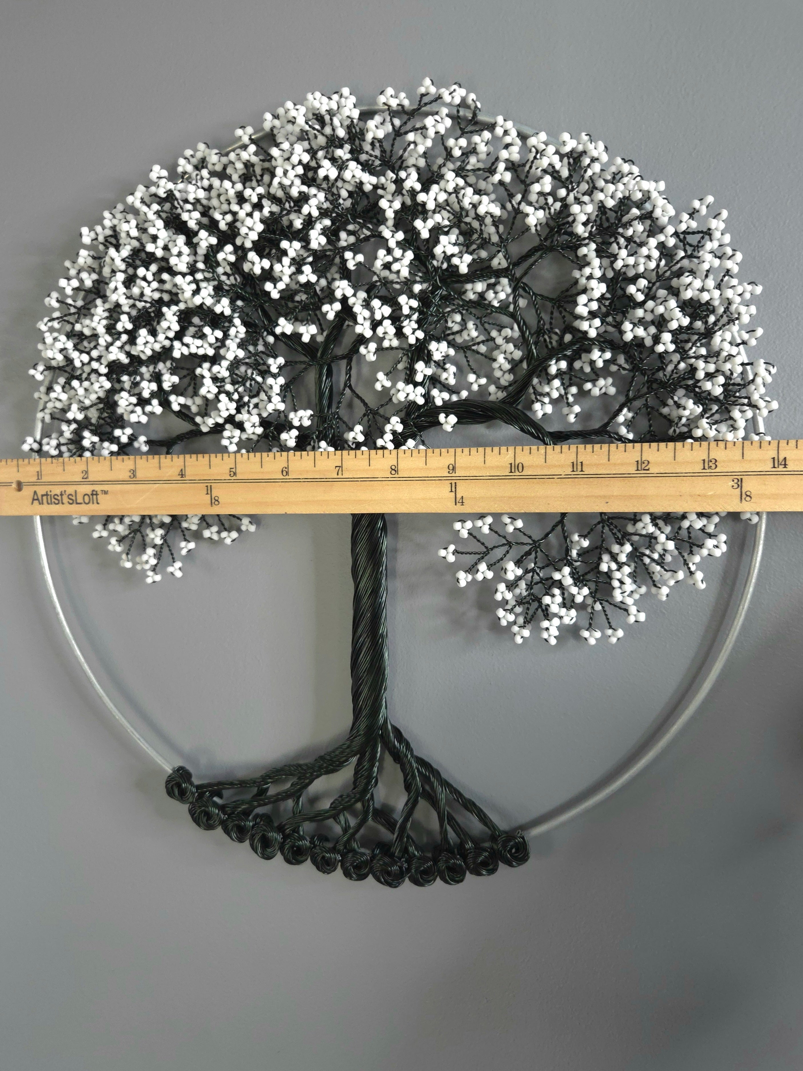 Decorative tree with white berries and a ruler for scale on a gray background