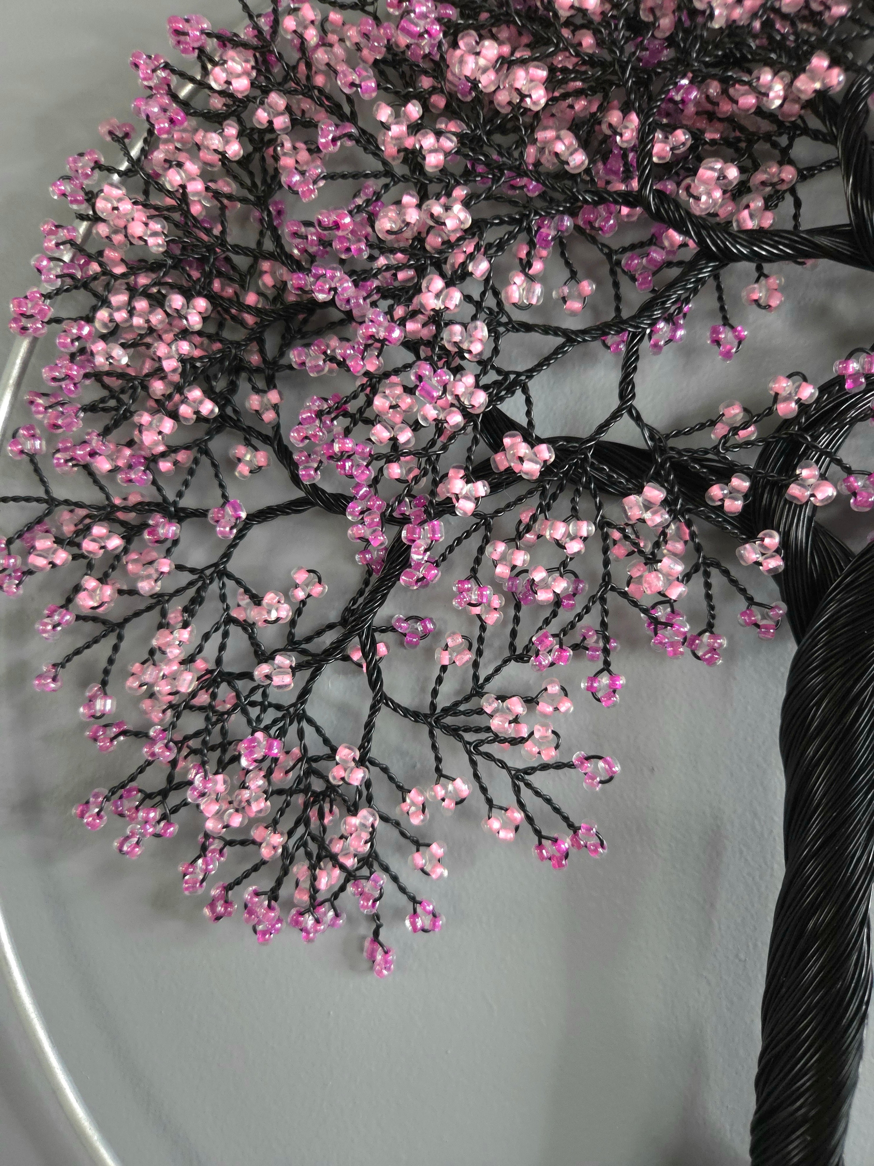 Decorative branch with pink and black beads on a gray background