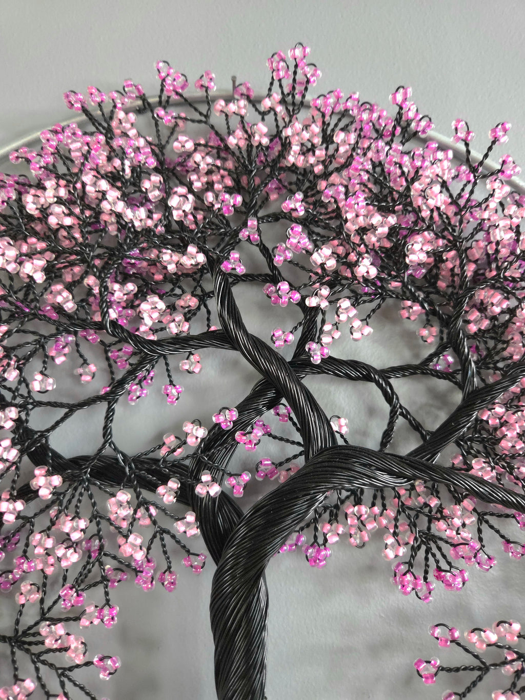 Embroidered tree design with pink flowers on a gray background