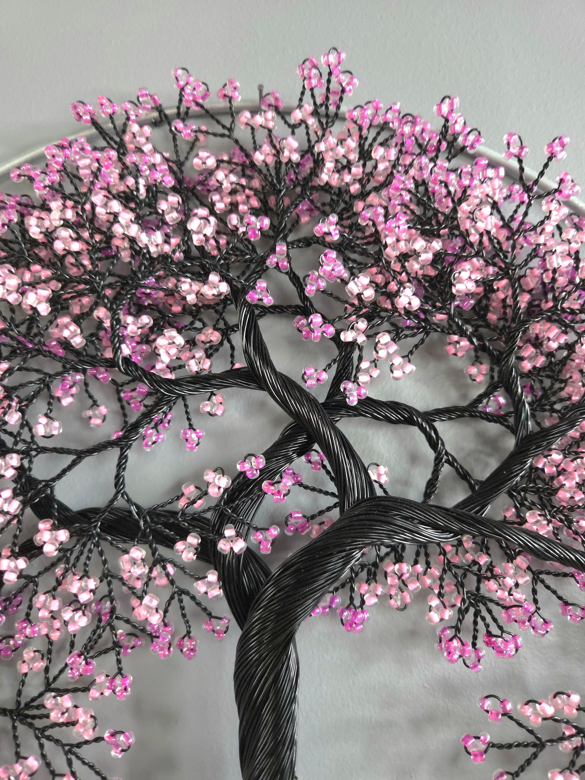 Embroidered tree design with pink flowers on a gray background