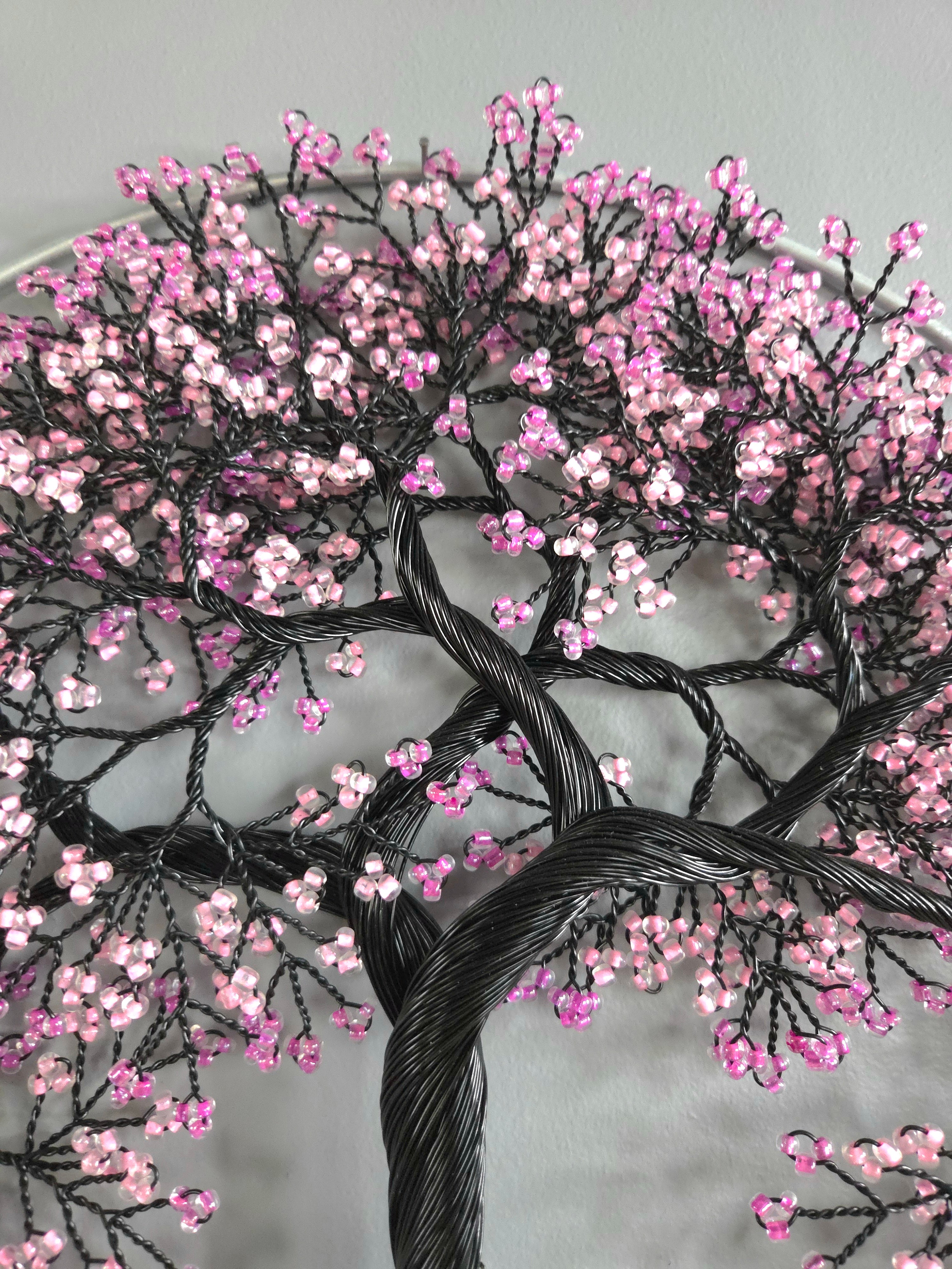 Embroidered tree design with pink flowers on a gray background